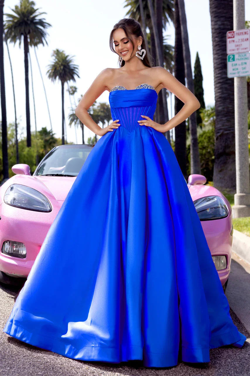 Model wearing cobalt blue corset gown in front of pink convertible 