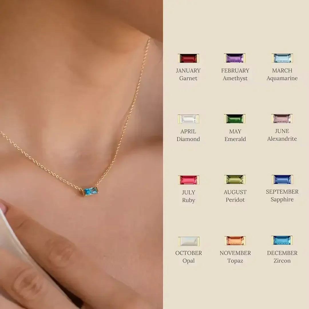 A gold necklace with a prominent blue gemstone rests on a person's neck, complemented by a chart of birthstones arranged by month and accompanied by their names.