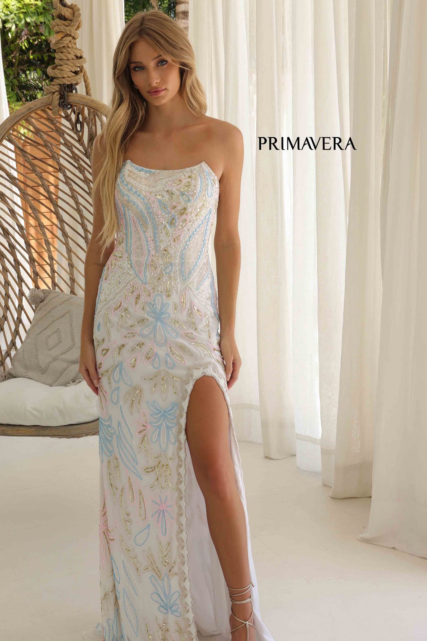 Woman wearing a floral dress with a high slit in a bright room, featuring the brand 'Primavera'.