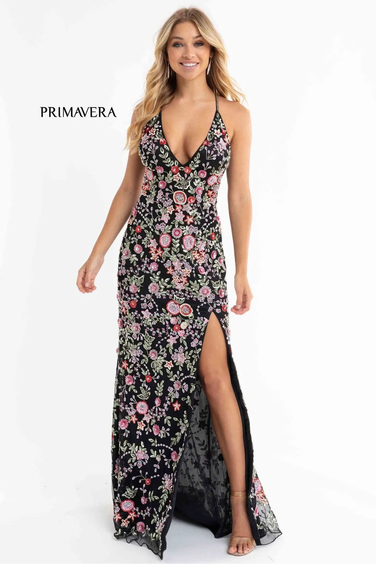 Woman wearing a floral evening gown with a slit on a white background, branded 'Primavera'.