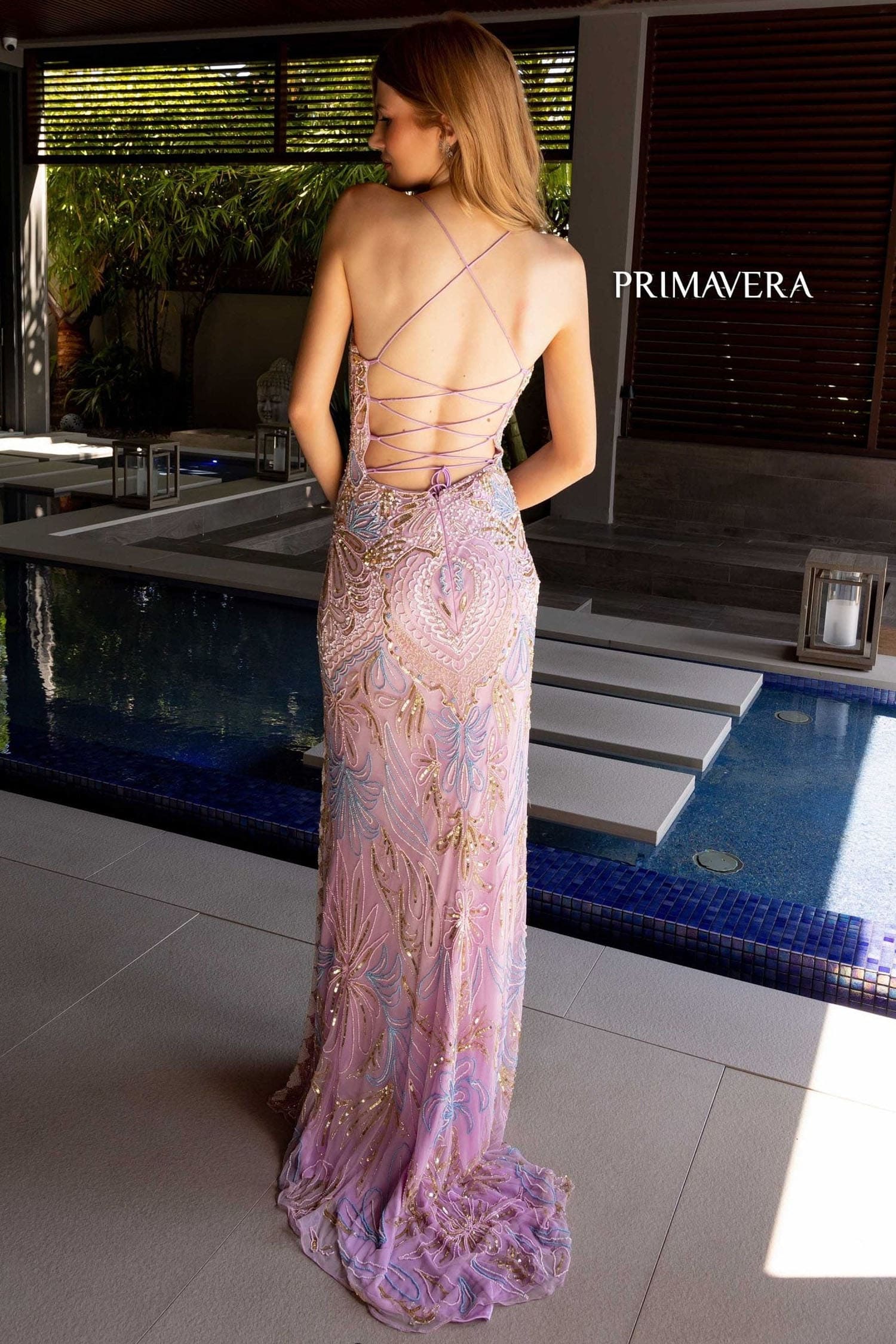 Woman in a floral evening gown by Primavera standing by a pool.