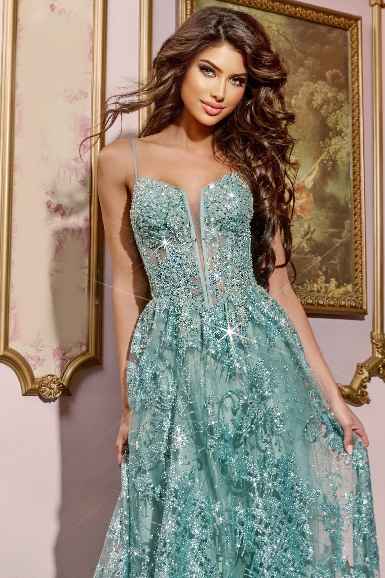 Woman wearing a sparkling teal dress in front of a decorative wall.