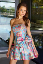 Woman wearing a floral strapless dress with a large bow in an outdoor setting