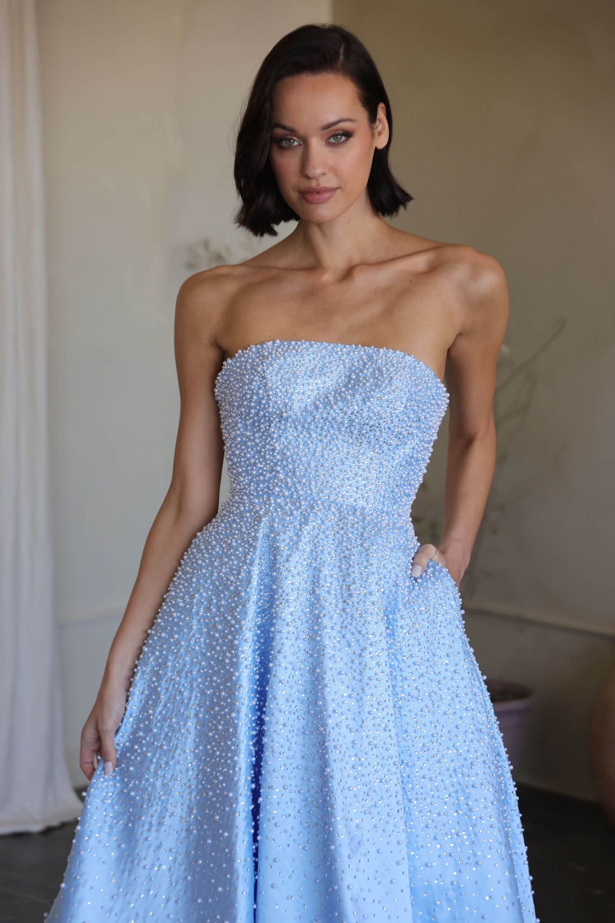 Woman wearing a light blue strapless gown in an indoor setting