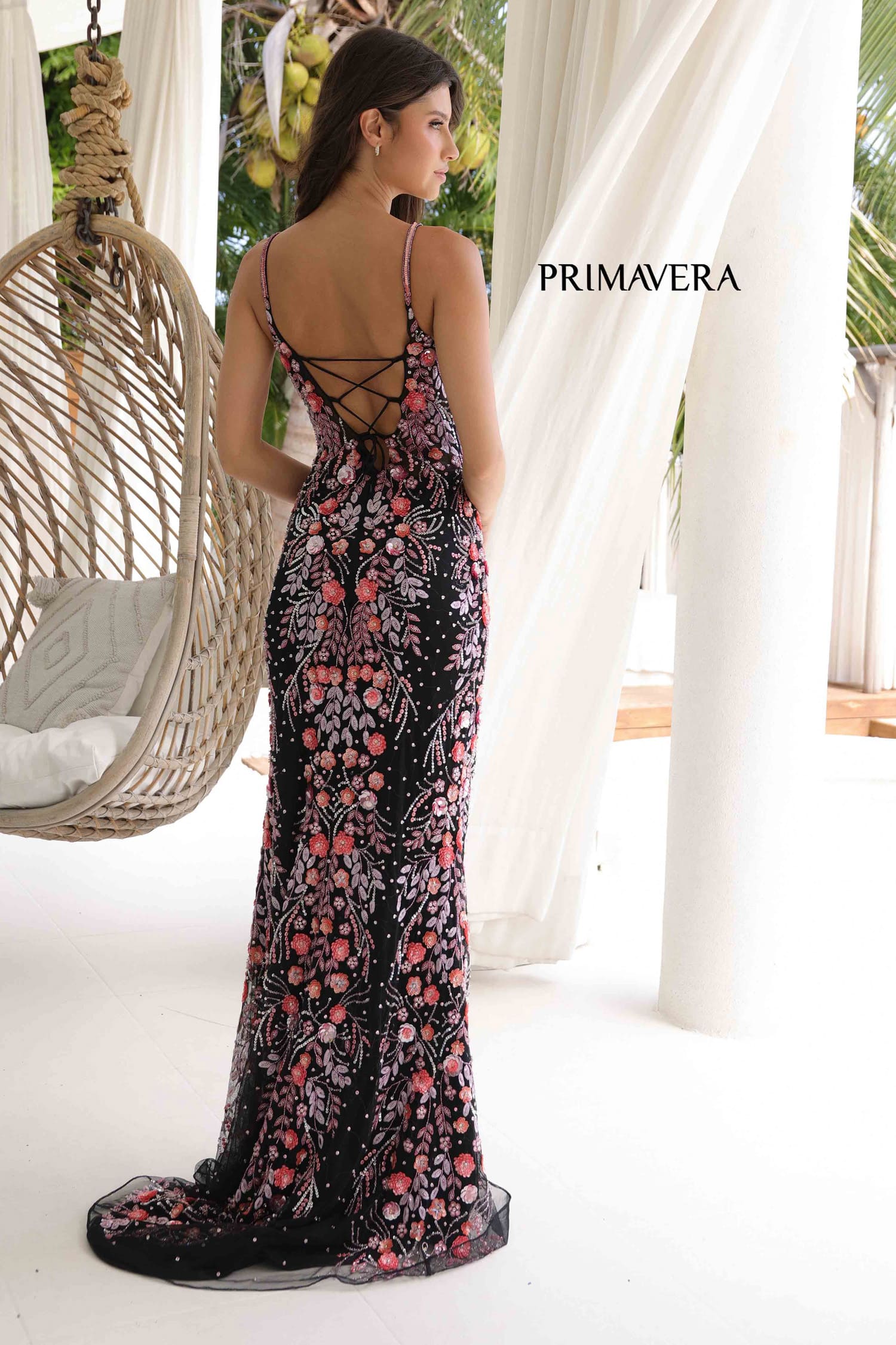 Woman wearing a floral dress with 'PRIMAVERA' branding in an outdoor setting.