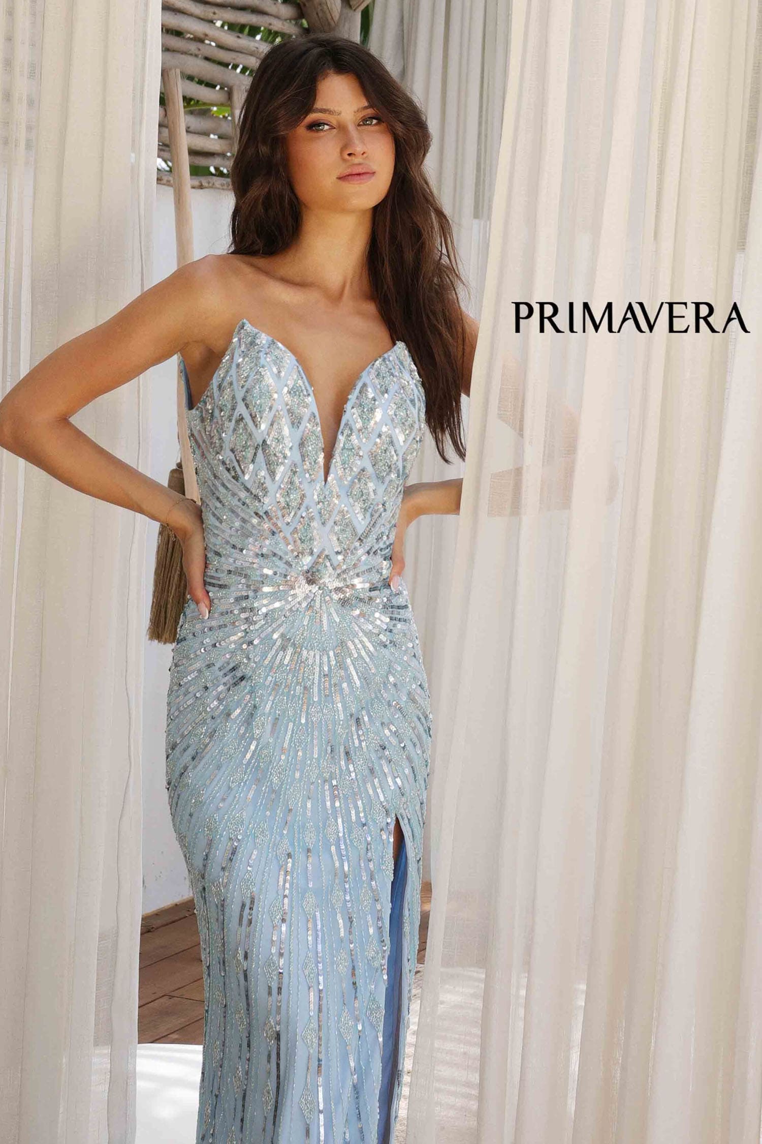 Woman wearing a sparkling blue evening gown with 'Primavera' branding.