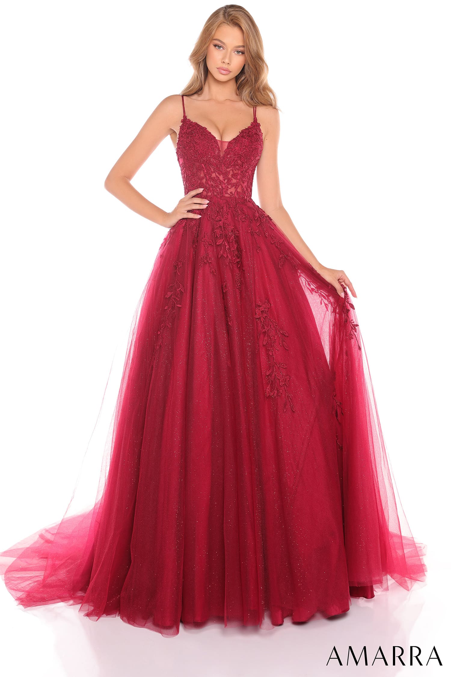 A woman modeling a deep burgundy red formal ball gown with a lace bodice, thin spaghetti straps, and a voluminous tulle skirt, shown against a plain white background.
