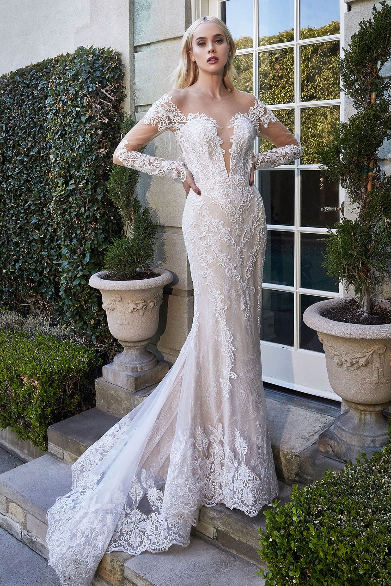 Woman in a white lace wedding dress standing outdoors.