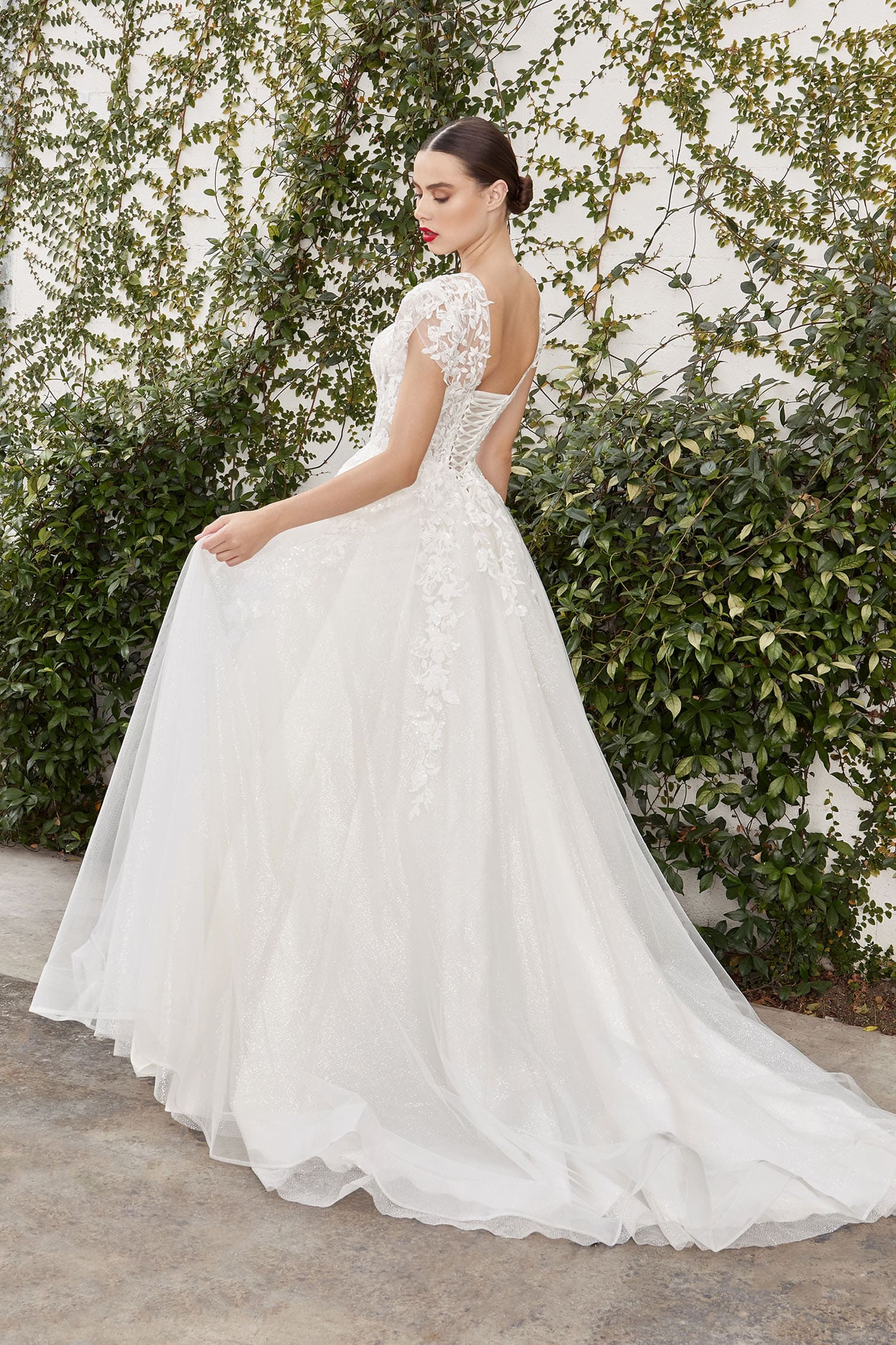 Woman in a white wedding dress standing against a green leafy background