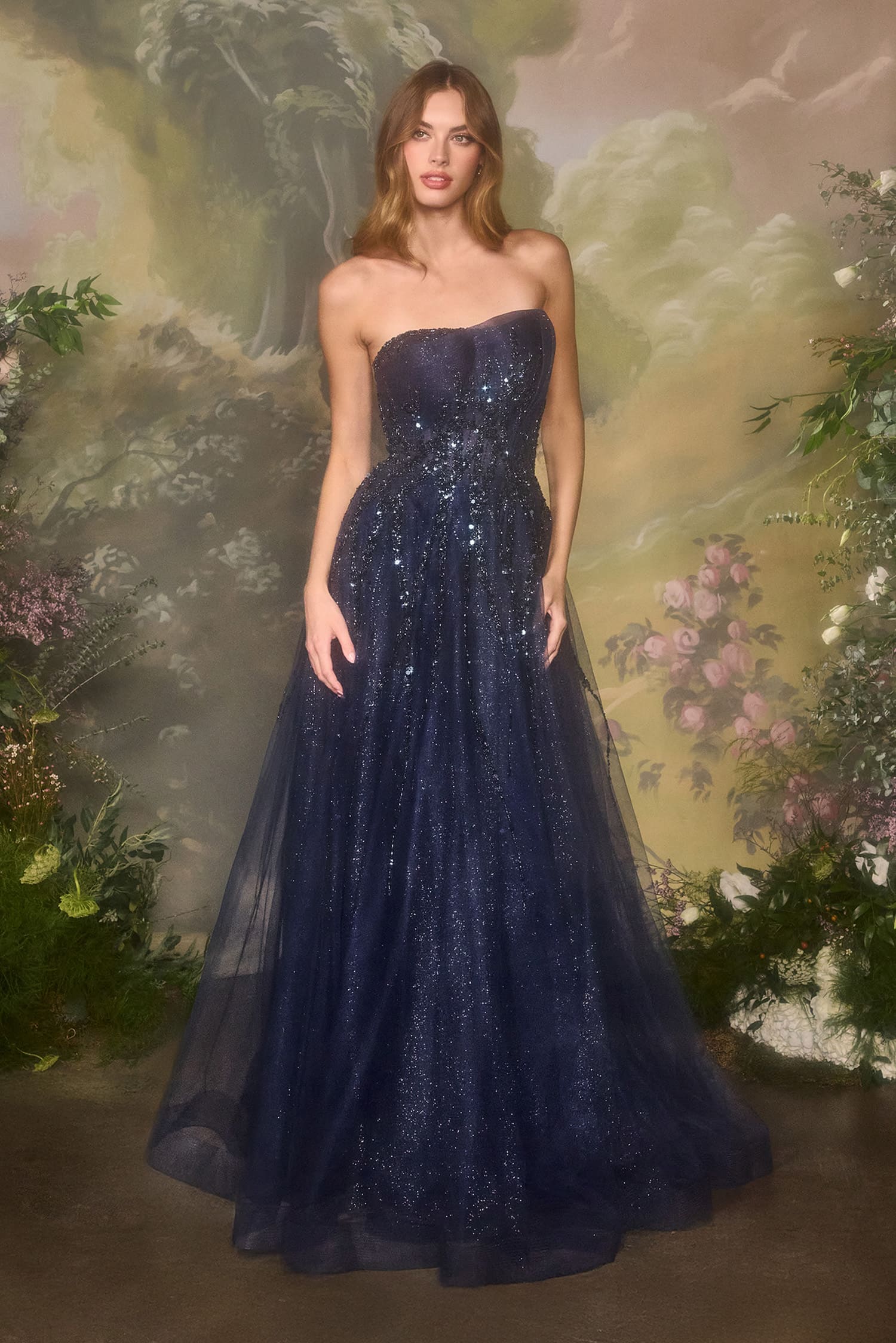 Woman wearing a strapless navy blue gown against a floral background