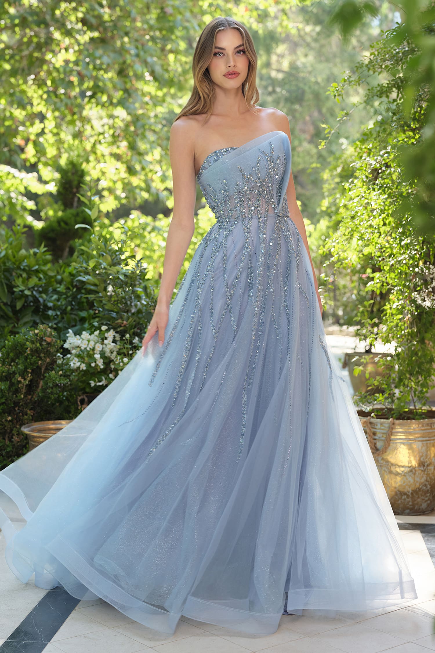 Woman wearing a light blue strapless gown with beaded details in an outdoor setting.