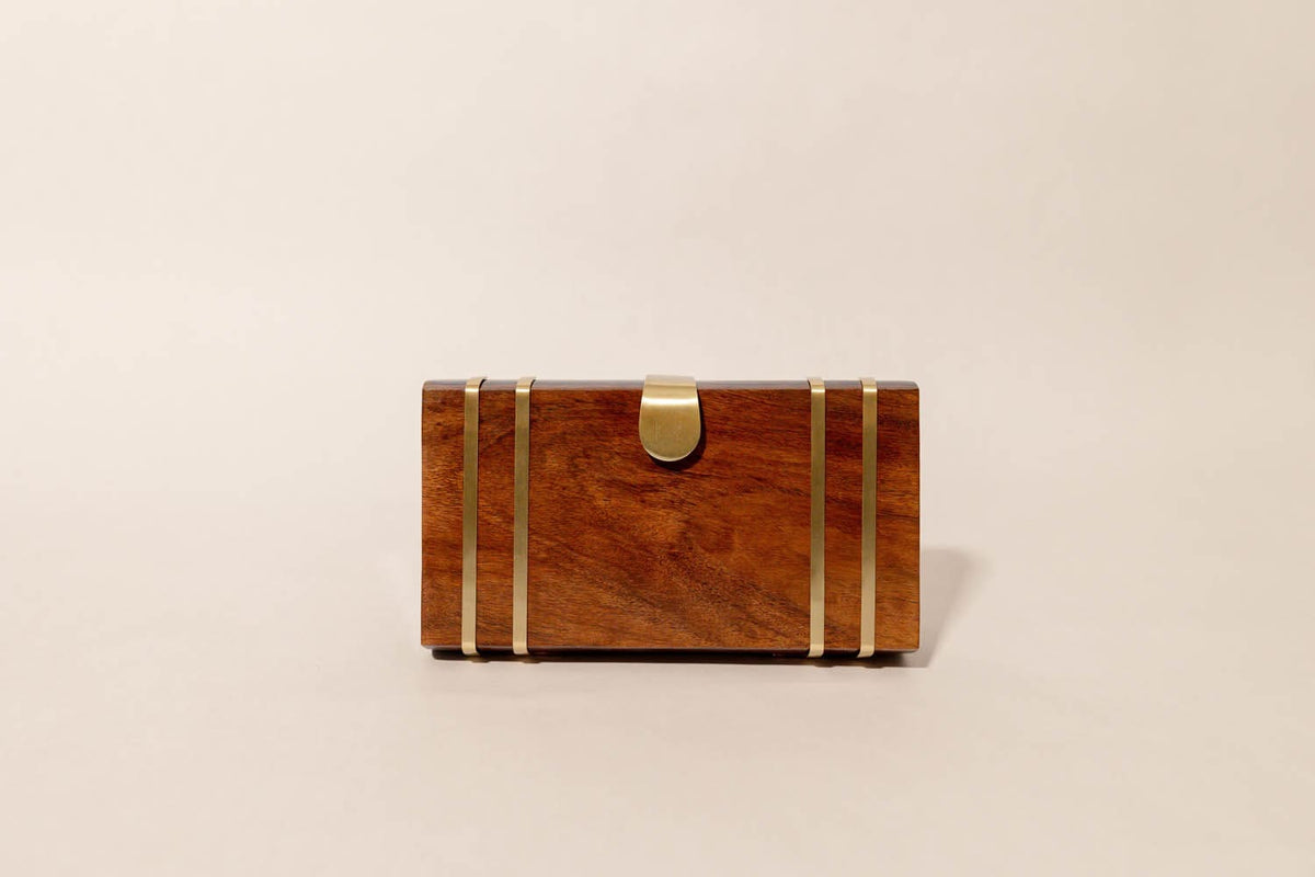 Wooden clutch with gold accents on a beige background