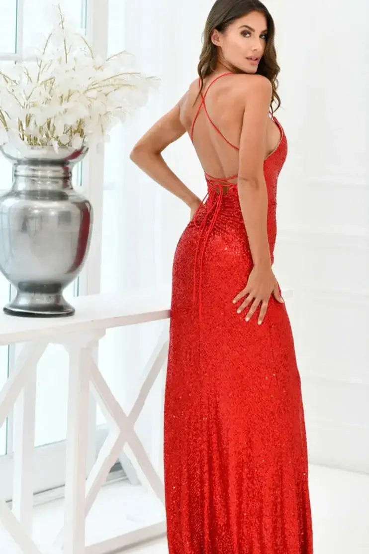 A woman stands in a fitted red sequined gown, facing away from the camera. She is next to a white table with a large decorative vase, surrounded by bright interiors and large windows.