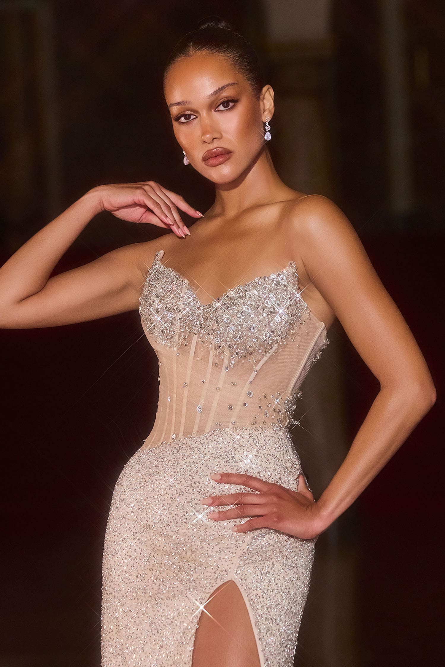 Model wearing a sparkling silver dress with a dark background