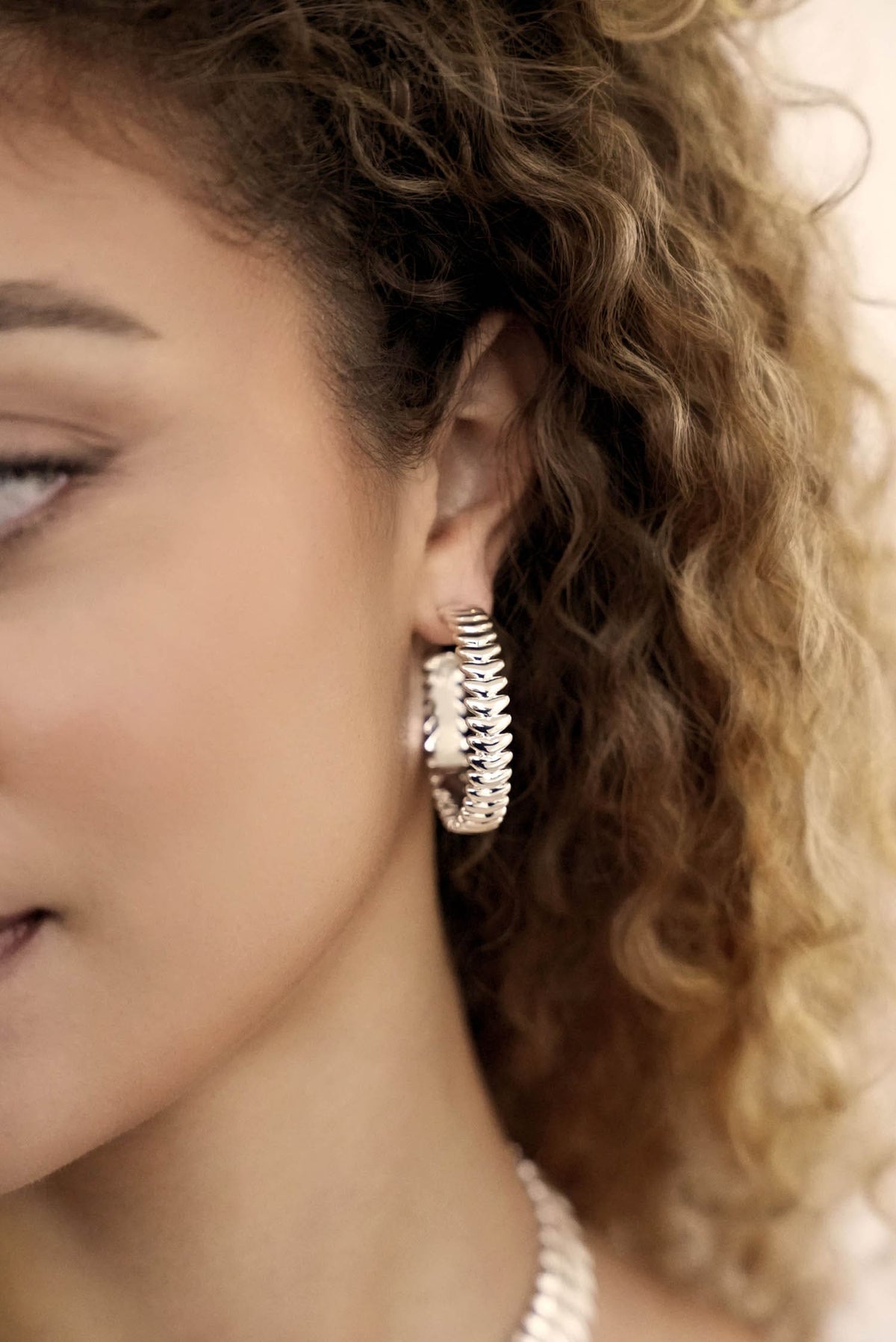 Close-up of a woman wearing a silver hoop earring with a blurred background