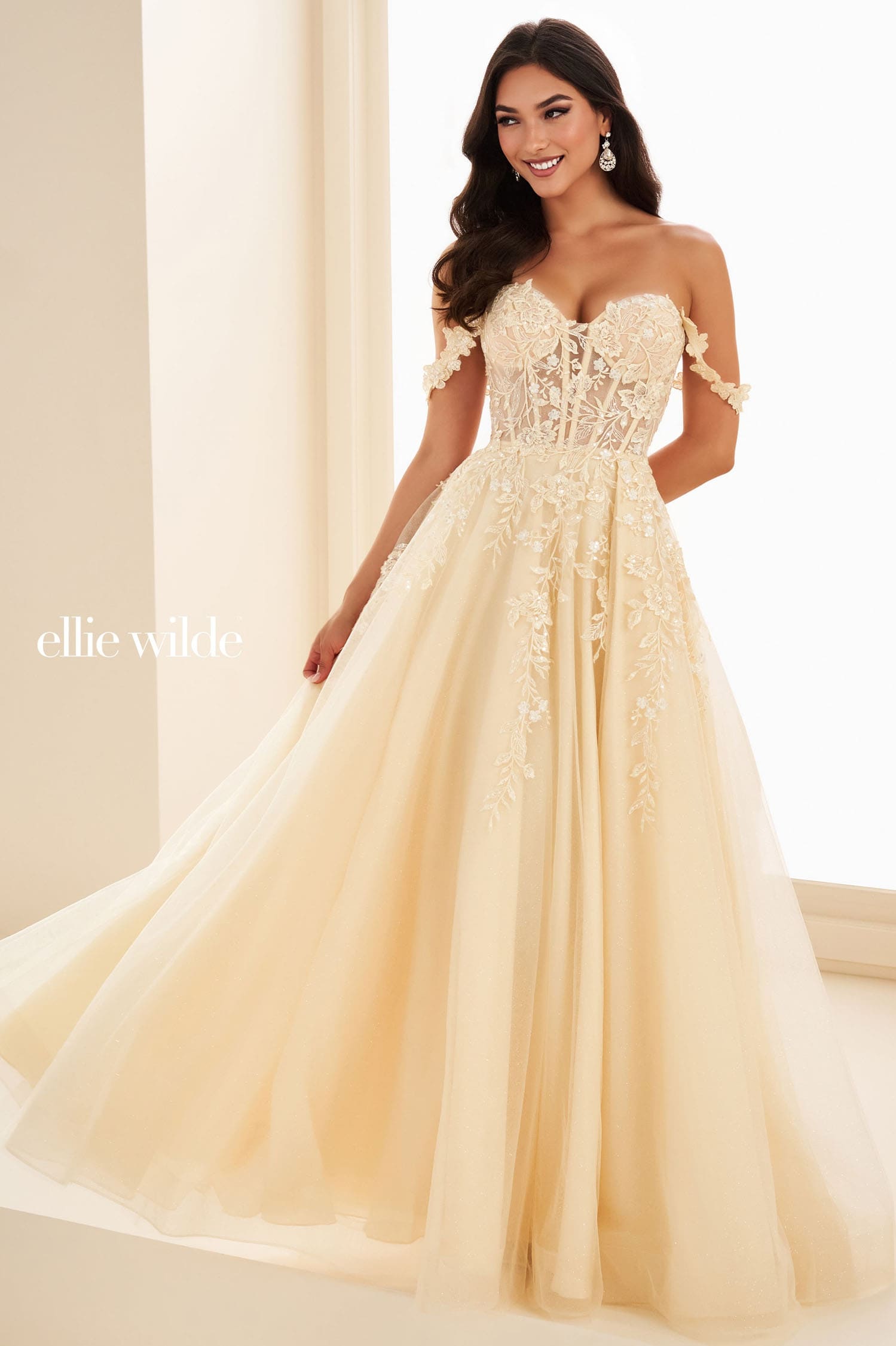 Woman wearing a beige floral one-shoulder gown with 'ellie wild' branding.