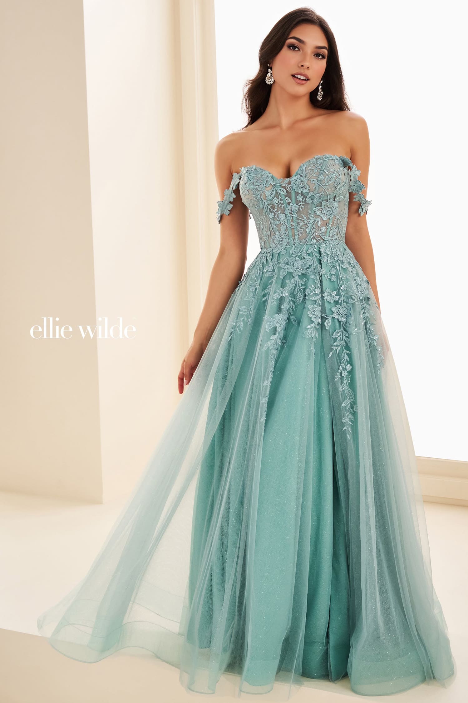 Woman wearing a light blue evening gown with intricate detailing, standing against a neutral background.