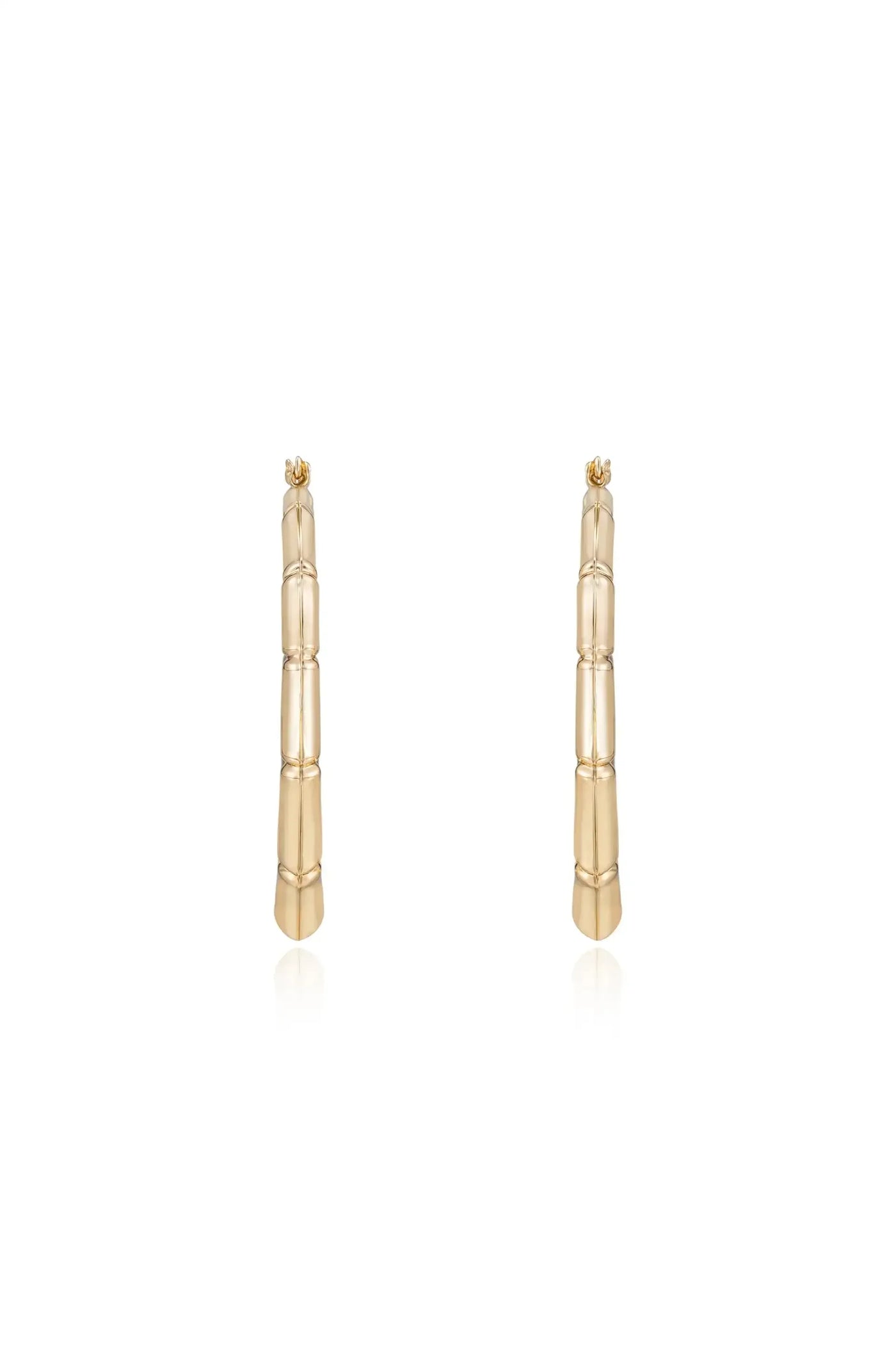 Gold earrings resembling bamboo stalks stand upright against a plain white background, showcasing their textured finish and polished shine, emphasizing an elegant, modern design.