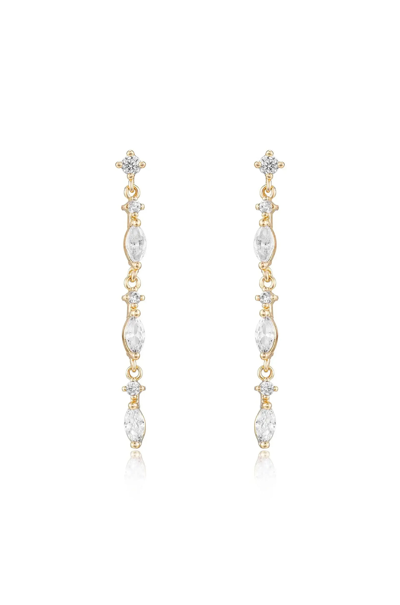 Long, elegant gold earrings feature a series of clear, sparkling gemstones arranged vertically. They hang gracefully, reflecting light, set against a plain, bright background.