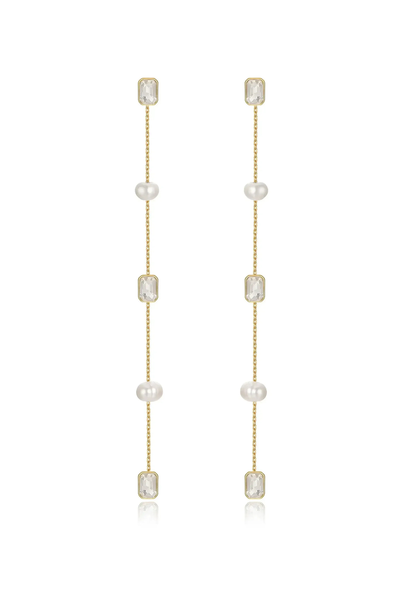 Gold earrings feature four pearl beads and two rectangular clear stones, hanging delicately in a vertical arrangement, reflecting light against a neutral backdrop.