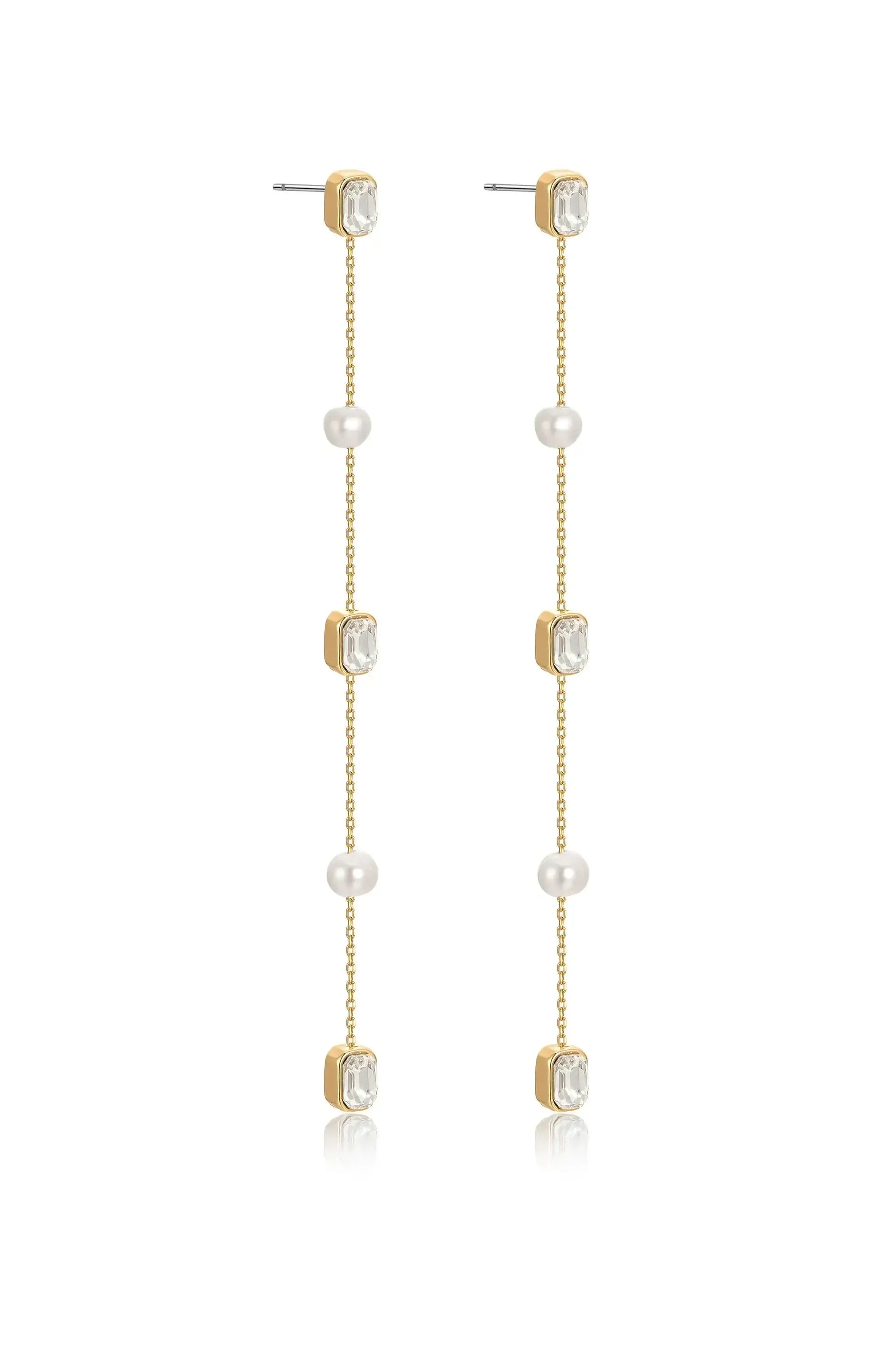 Long, elegant earrings feature alternating gold, crystal, and pearl elements. They dangle gracefully, reflecting light, suitable for formal or festive occasions. The background is neutral, emphasizing the earrings' design.