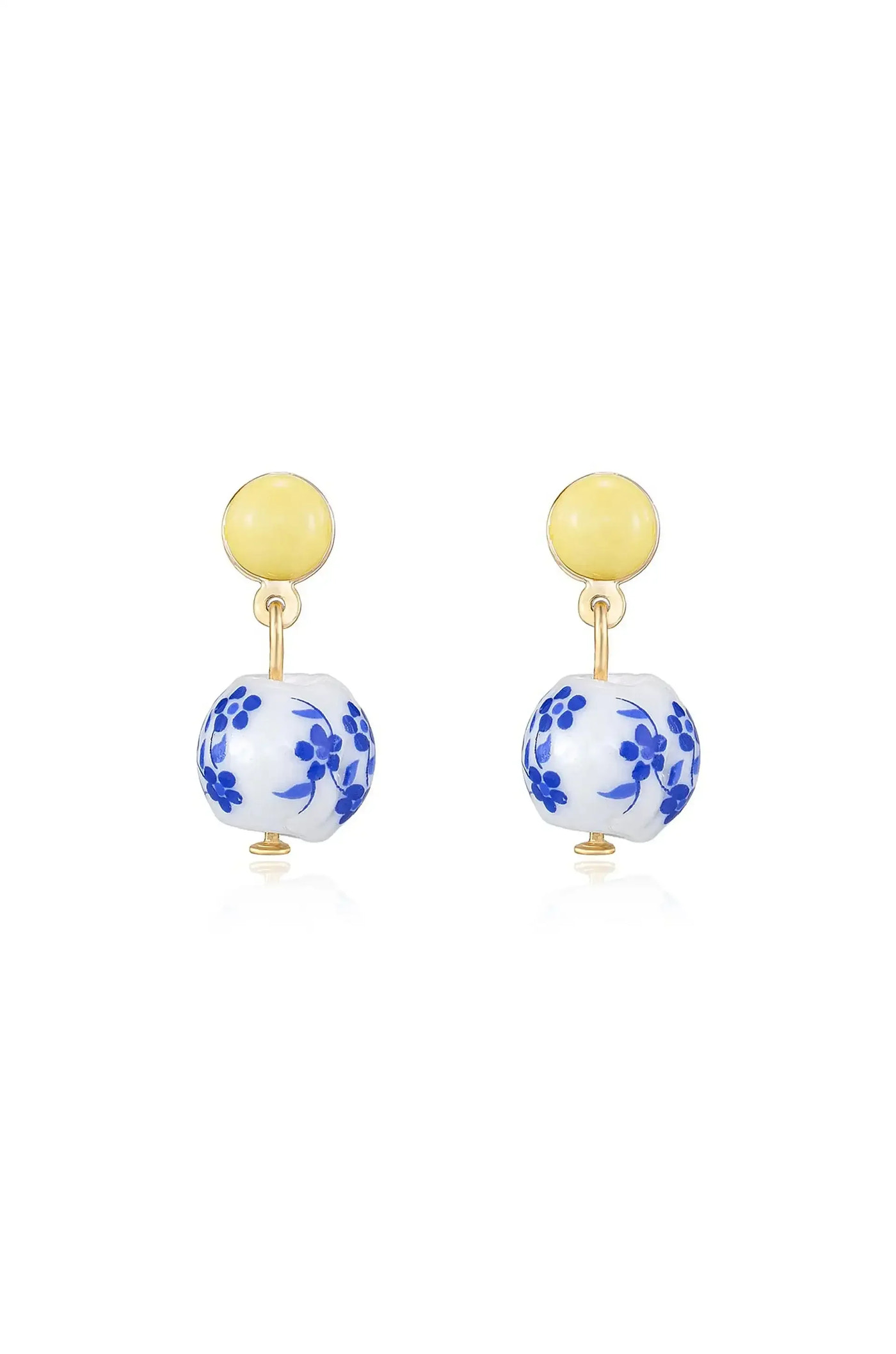 Gold-tone earrings feature a yellow circular top with a blue floral-patterned porcelain ball dangling below. They appear on a reflective surface, highlighting their design and materials.