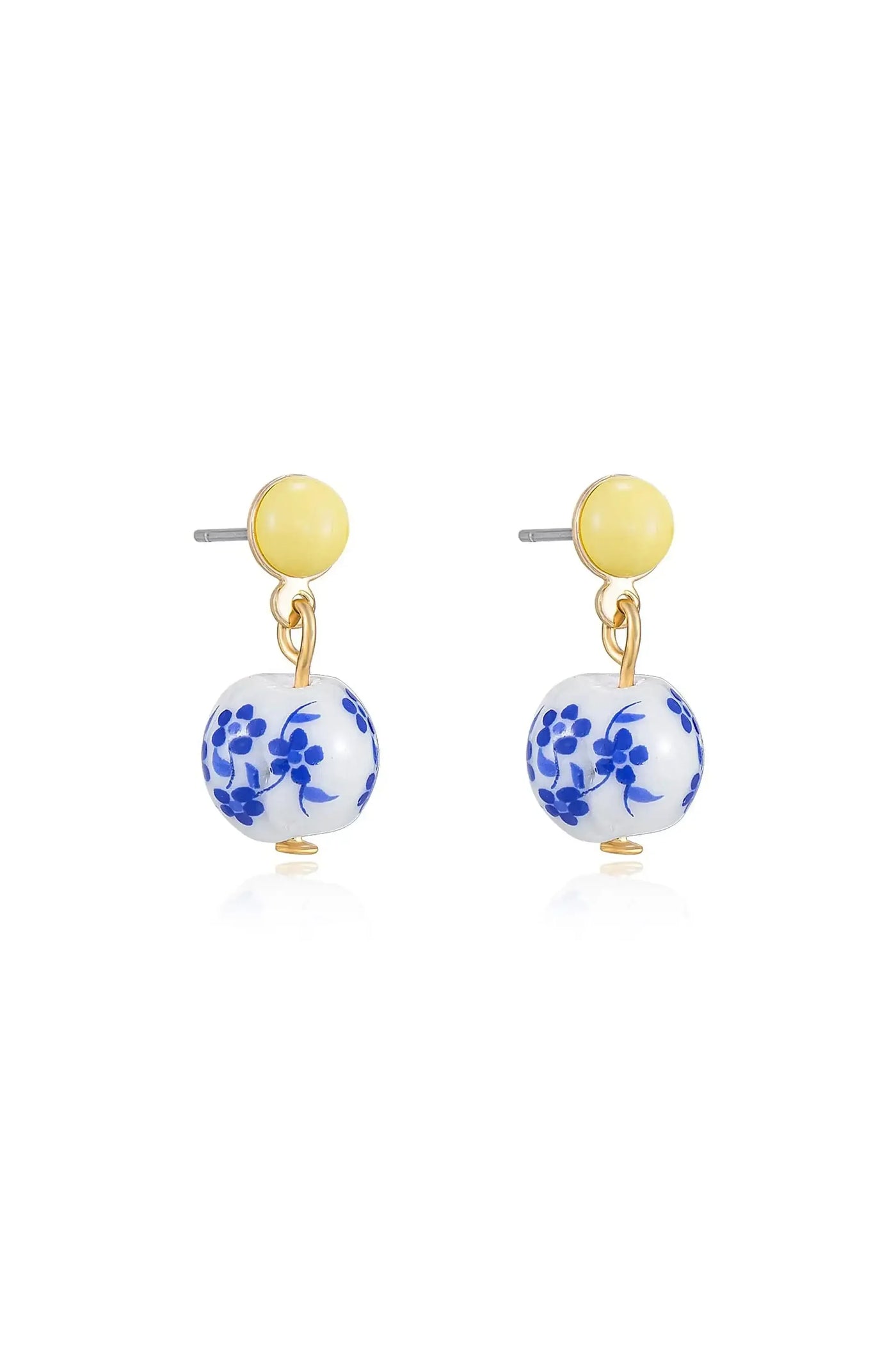 Two earrings are displayed. Each features a yellow circular stud at the top, with a hanging white bead adorned with blue floral patterns below, set against a plain background.