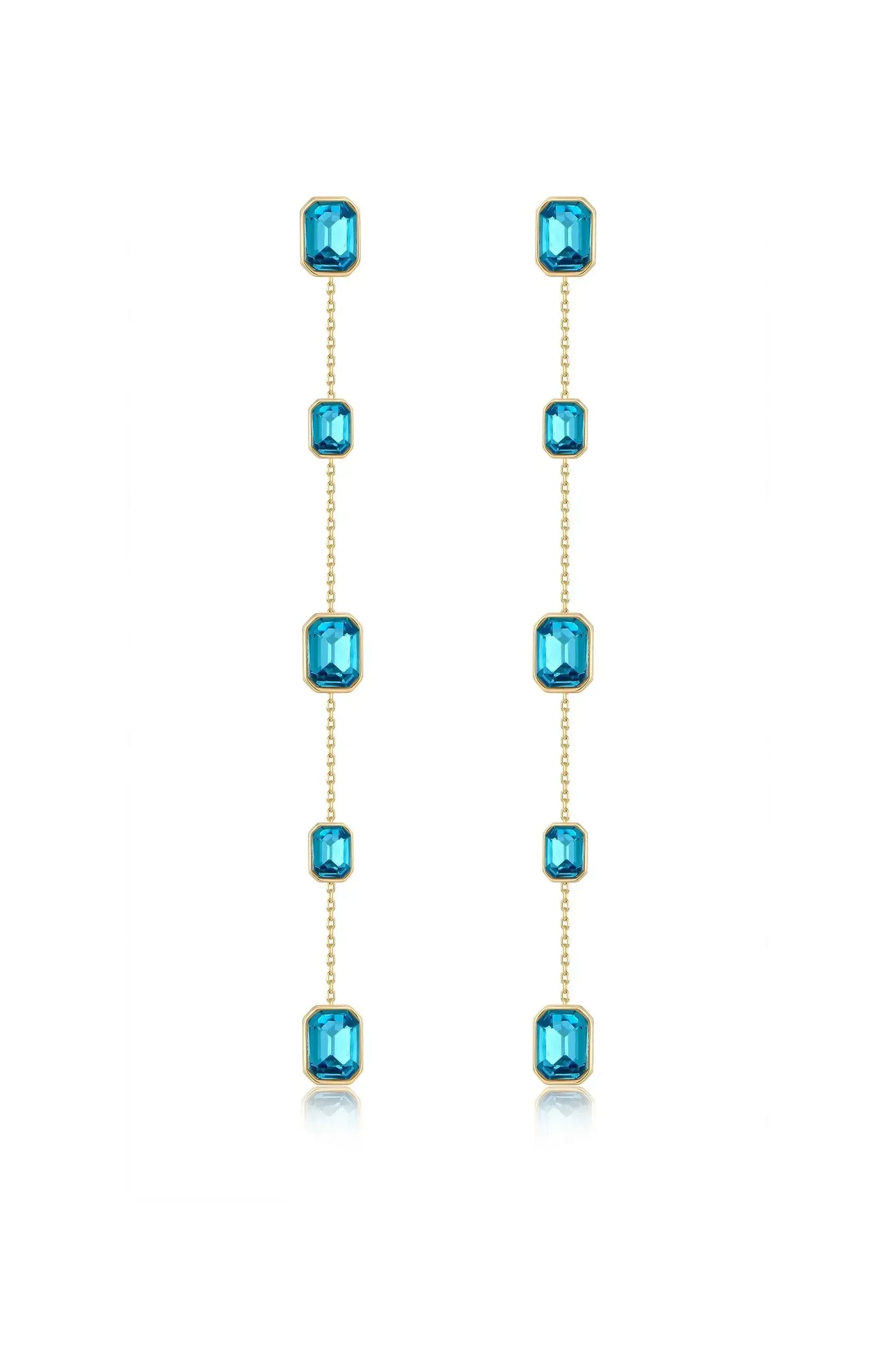 Dangling earrings feature a series of shimmering blue gems set in gold, elegantly hanging down in a vertical arrangement against a white background, highlighting their refined craftsmanship.