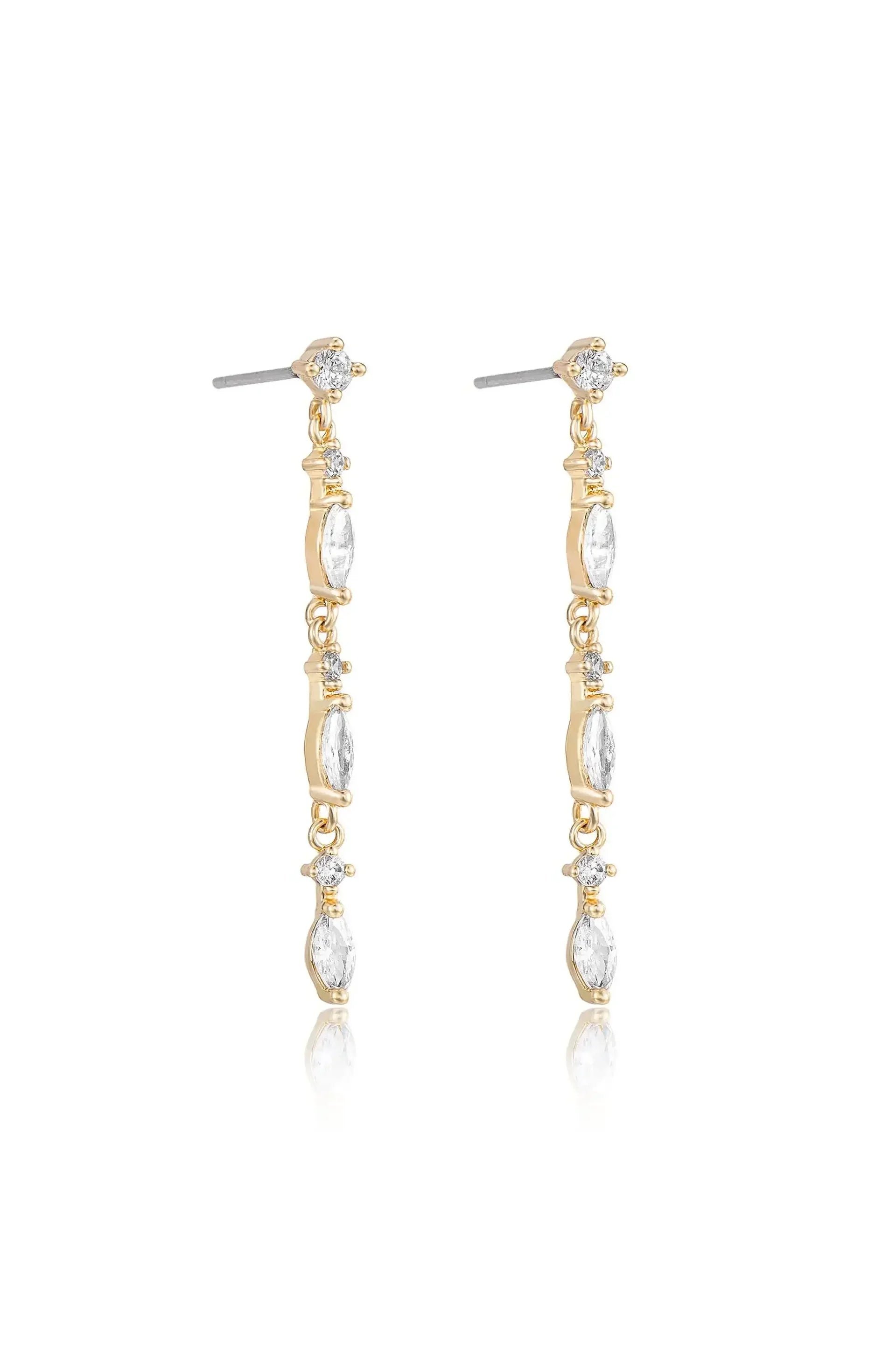 Dangle earrings are showcased, featuring elongated gold links adorned with clear gemstones. They are positioned against a light backdrop, reflecting a subtle shine.