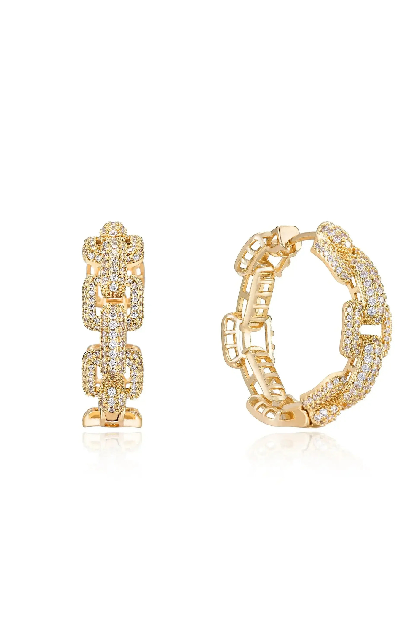 A pair of gold earrings, one with a chain-like design and the other featuring a studded pattern, rests on a reflective surface, highlighting their intricate details and shine.