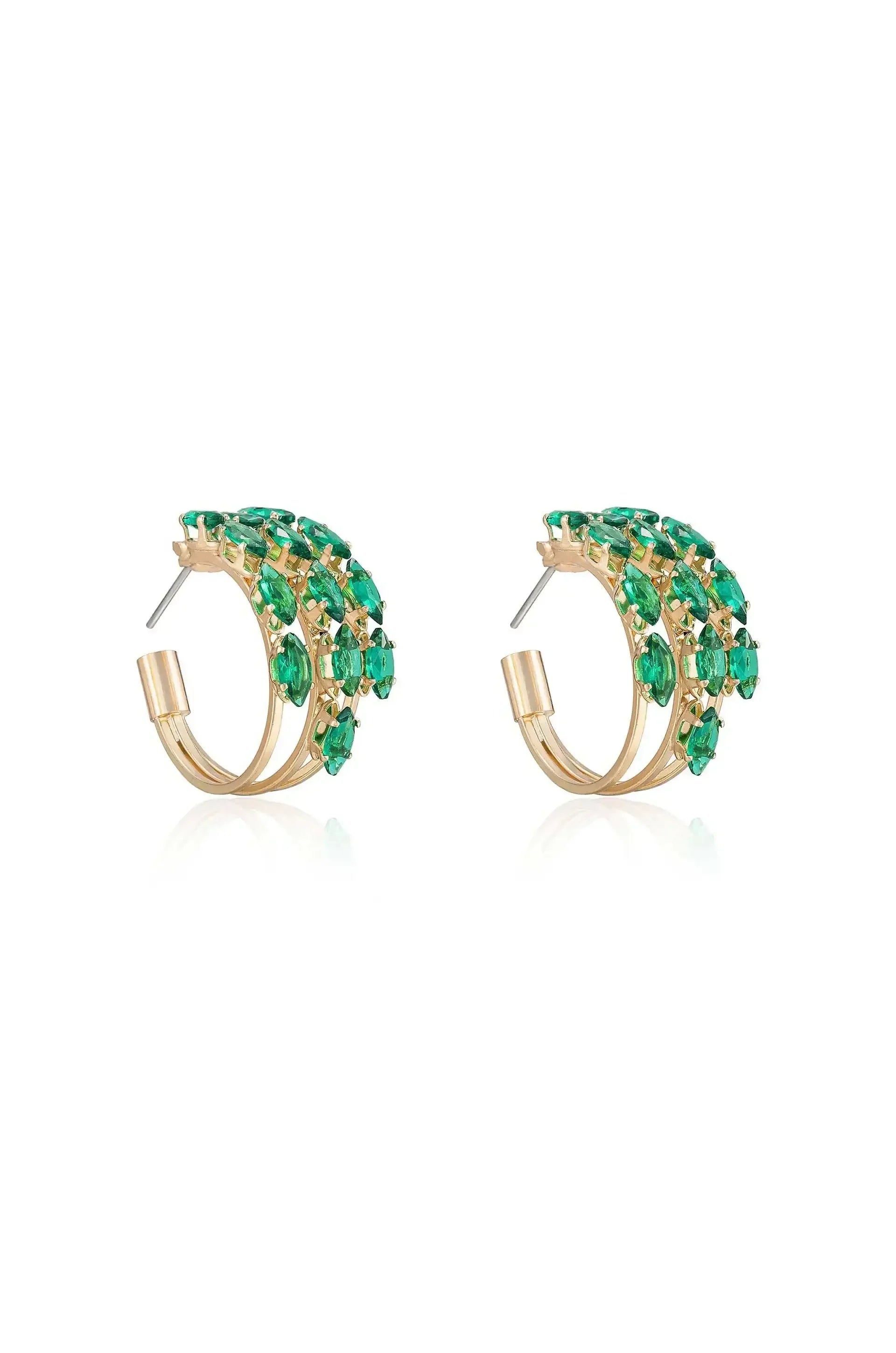 Golden hoop earrings, adorned with vibrant green gemstones, are displayed together. The earrings shimmer against a white background, highlighting their elegant design and intricate detailing.