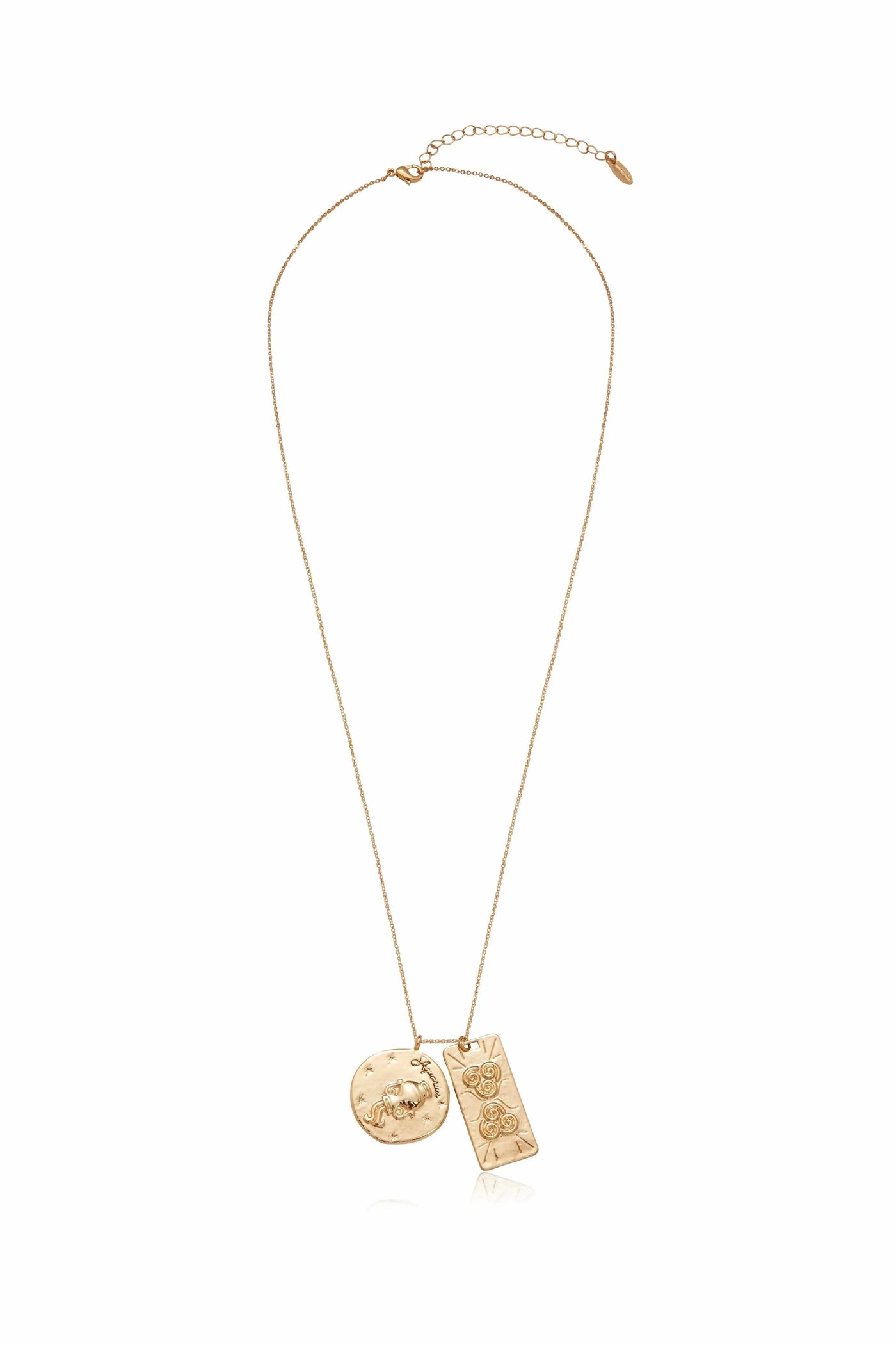 A gold necklace displays two pendants: a circular one featuring a design of a face and stars, and a rectangular one with swirls, hanging from a delicate chain.