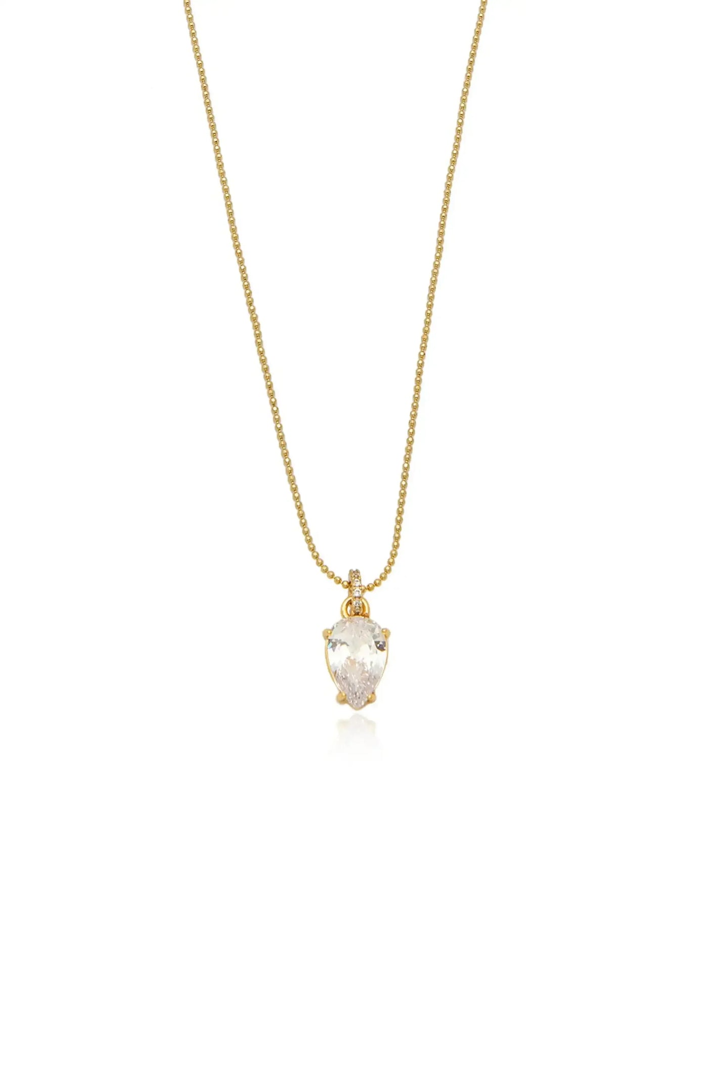 A gold necklace features a pear-shaped crystal pendant, elegantly suspended and catching light, creating a shimmering effect. The design is simple yet sophisticated, suitable for various occasions.