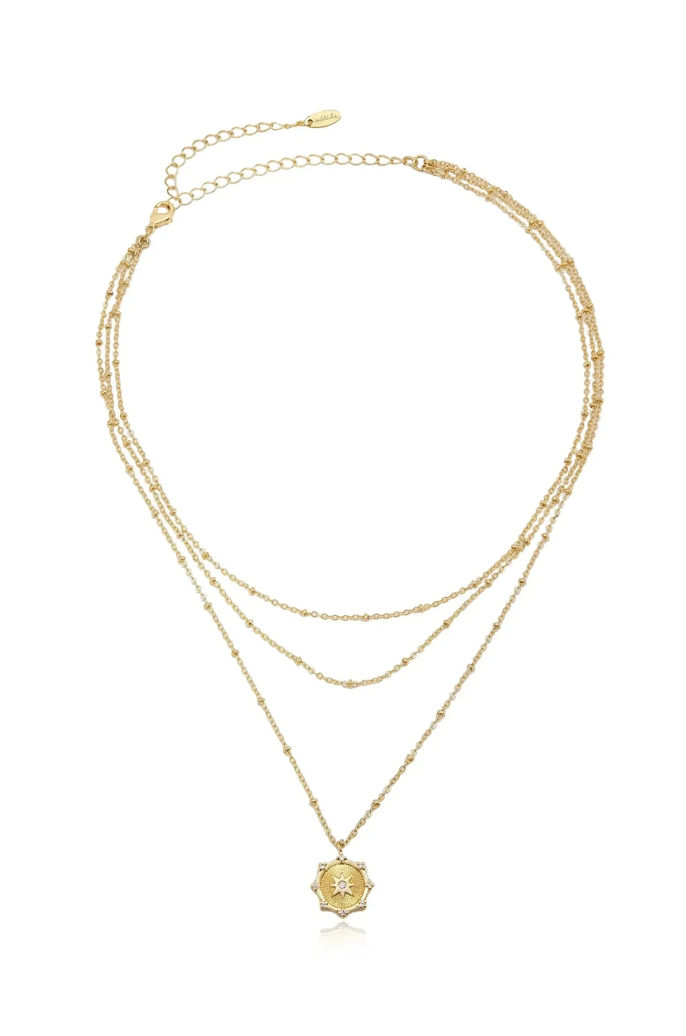 A gold layered necklace features three delicate chains, adorned with small beads, and a central star-shaped pendant with intricate designs and a gemstone in the center against a white background.