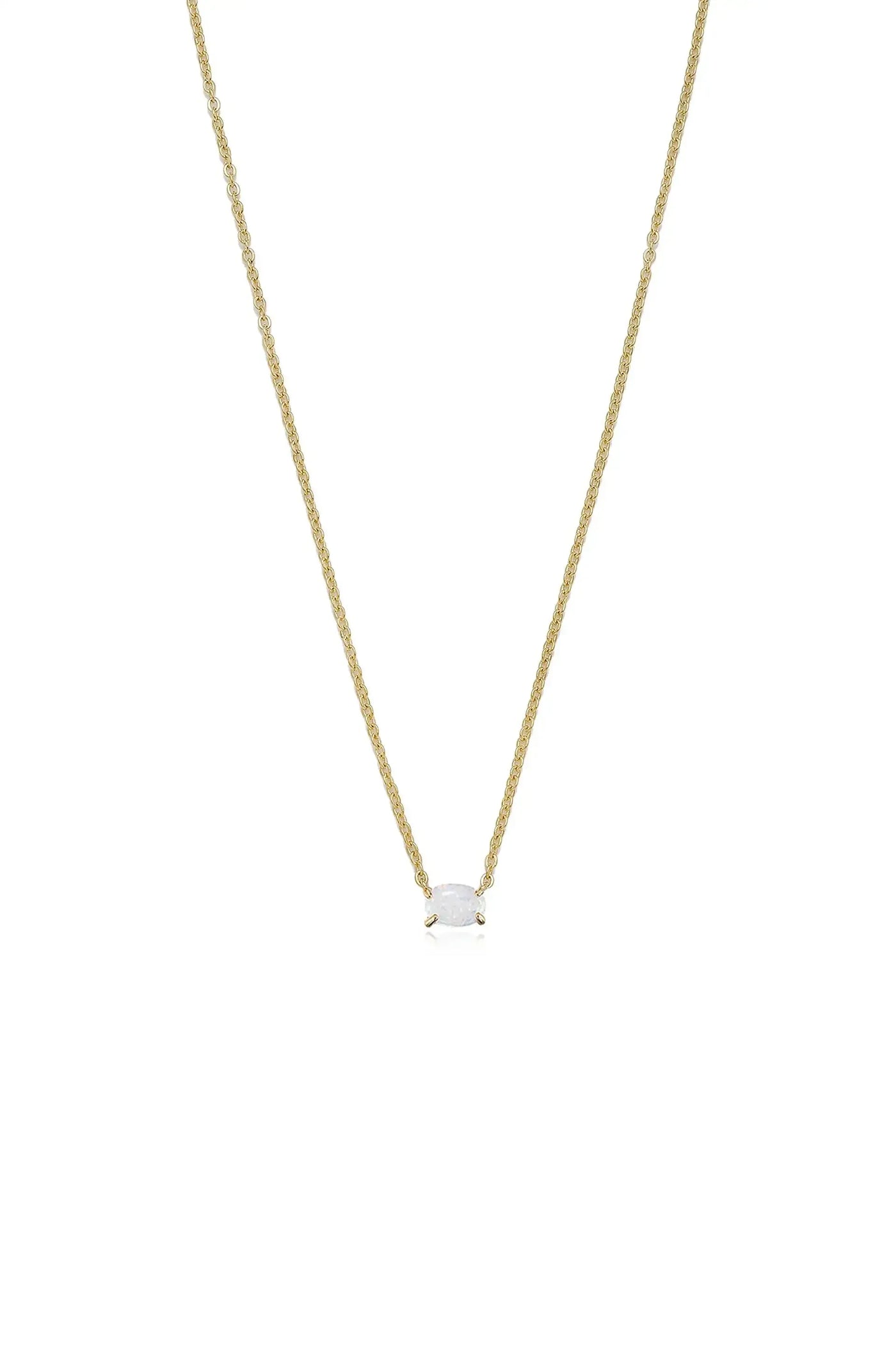 A delicate gold necklace features a central oval gemstone, suspended from a fine chain. It rests against a plain white background, highlighting its elegance and shimmering details.