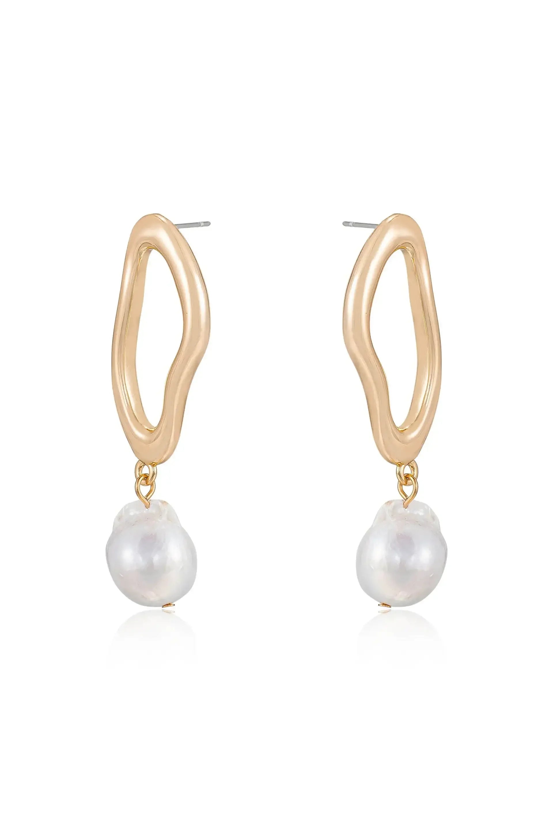 Gold hoop earrings feature an organic, wavy design with a dangling irregularly shaped white pearl. They are displayed against a simple, reflective background, emphasizing their elegance.