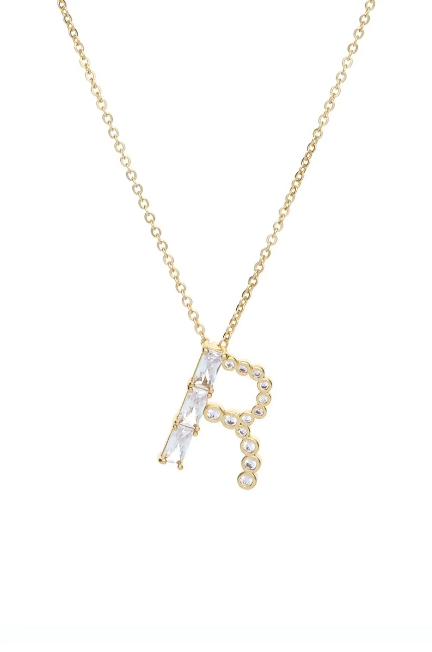 A gold necklace features a stylized letter "R" adorned with clear, sparkling stones. It hangs against a plain white background, emphasizing the jewelry's design and shine.