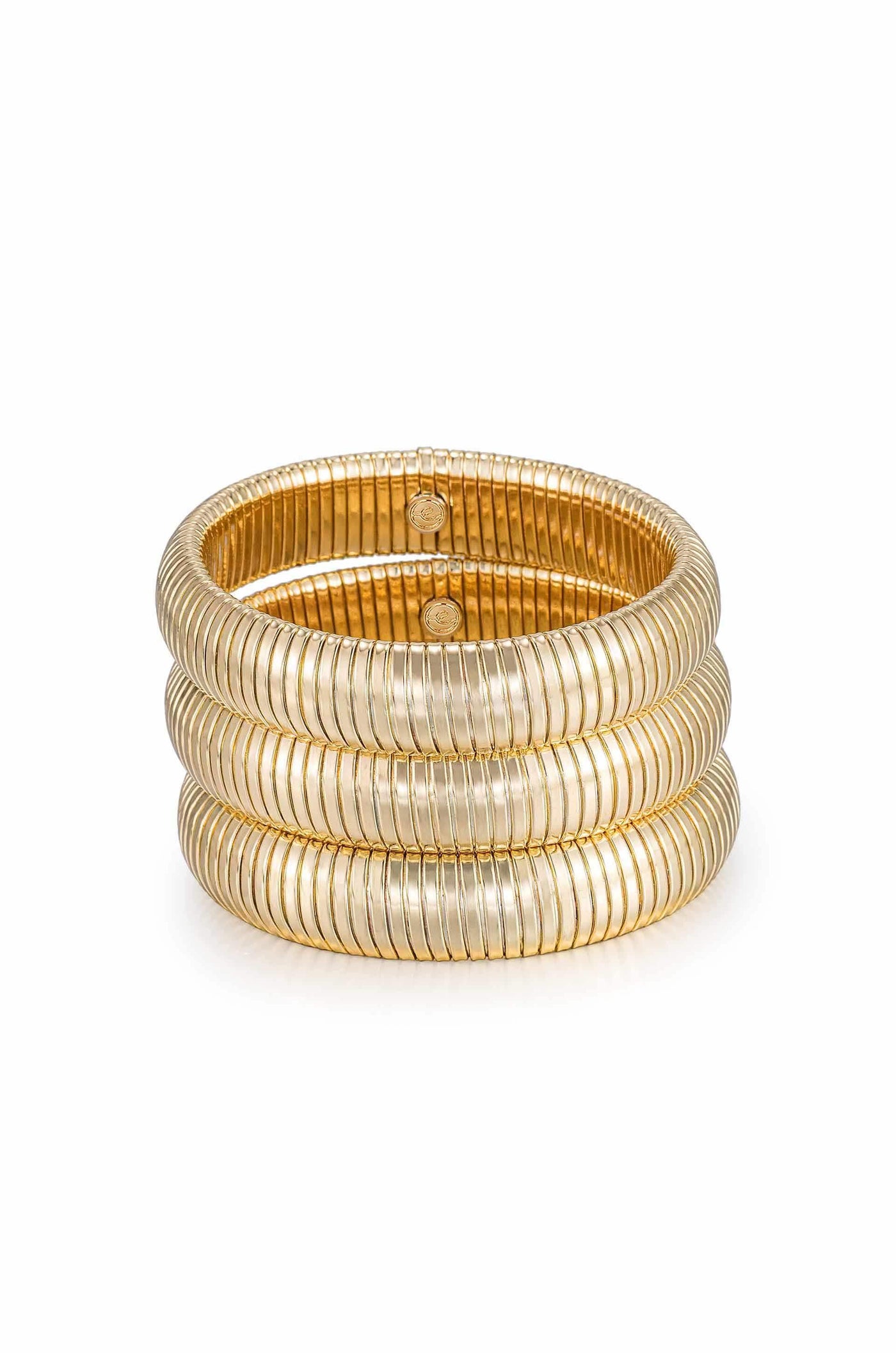 A set of three golden bangles stacked together, showcasing a ribbed design. The bangles rest on a smooth, light surface, highlighting their shiny metallic finish.