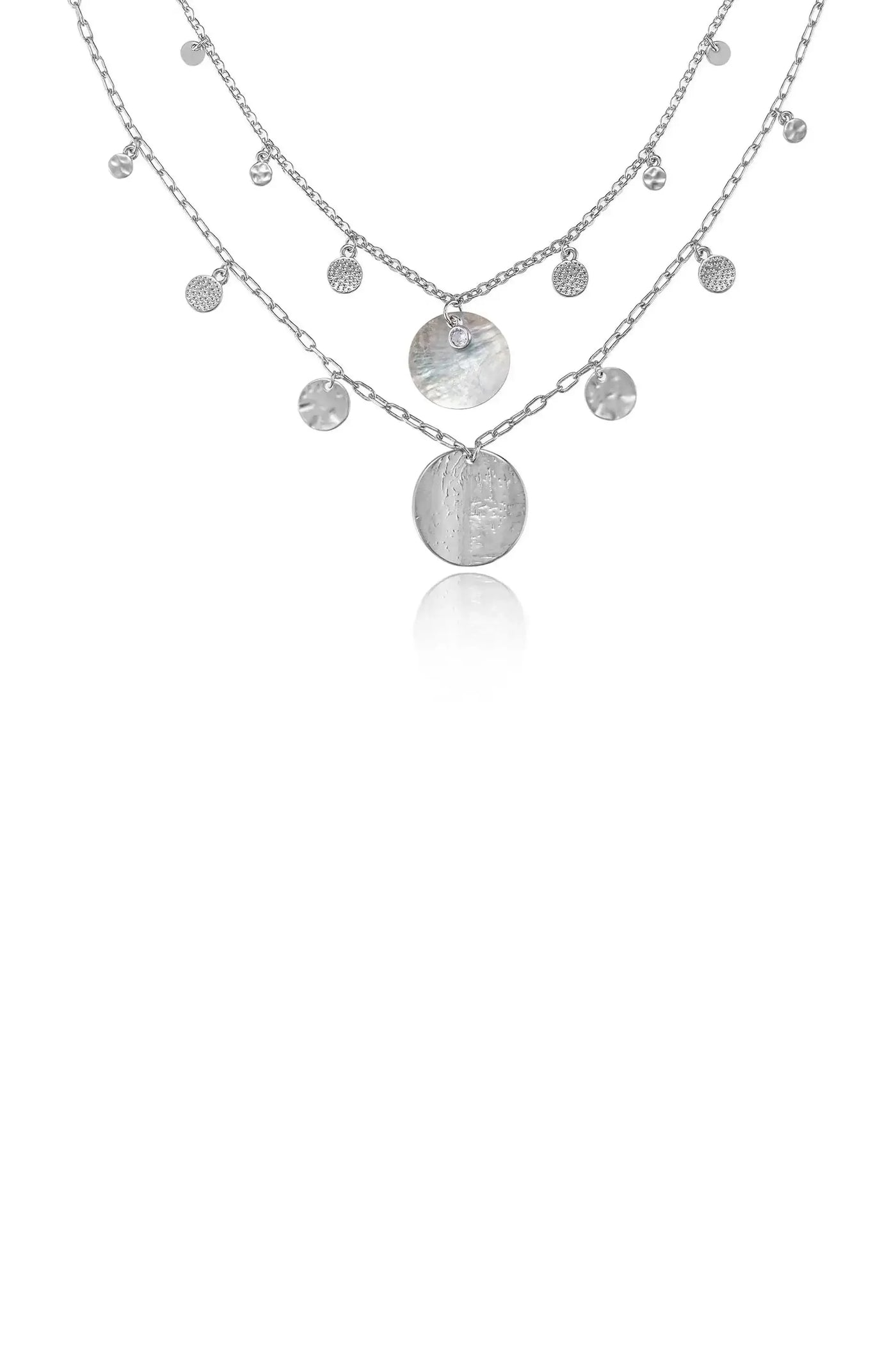 A layered silver necklace features multiple chains with decorative circular pendants and small gems, suspended in a reflective space, emphasizing its elegant design and shine.