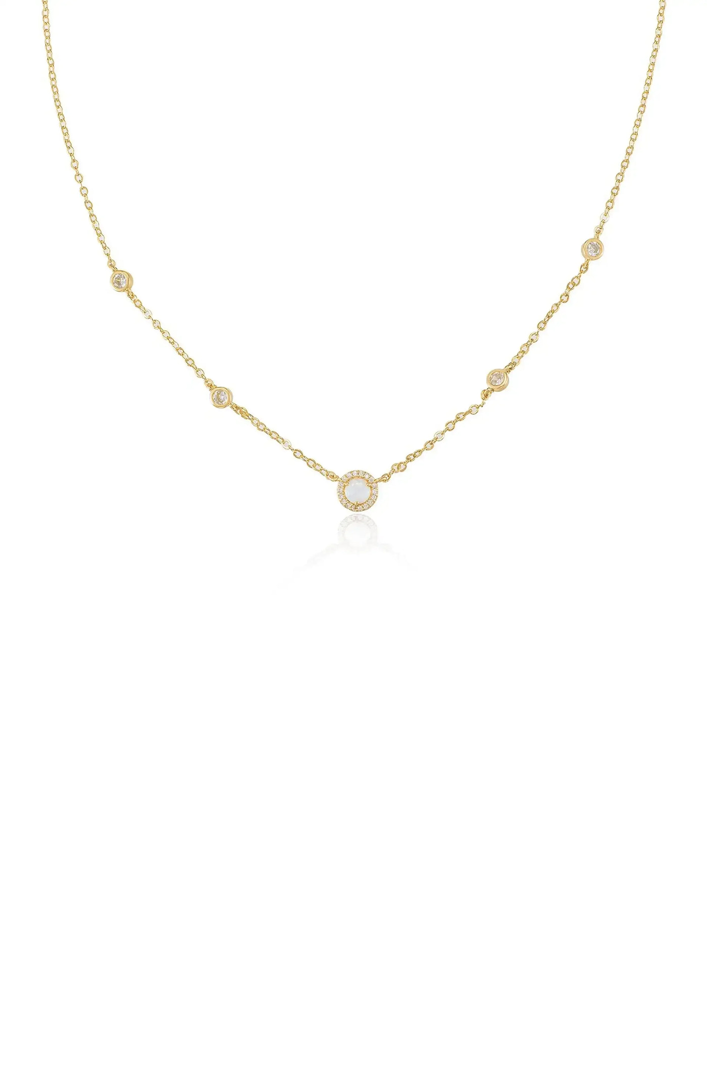A delicate gold necklace features a circular pendant surrounded by smaller stones, elegantly draping with a reflective sheen against a plain white background.