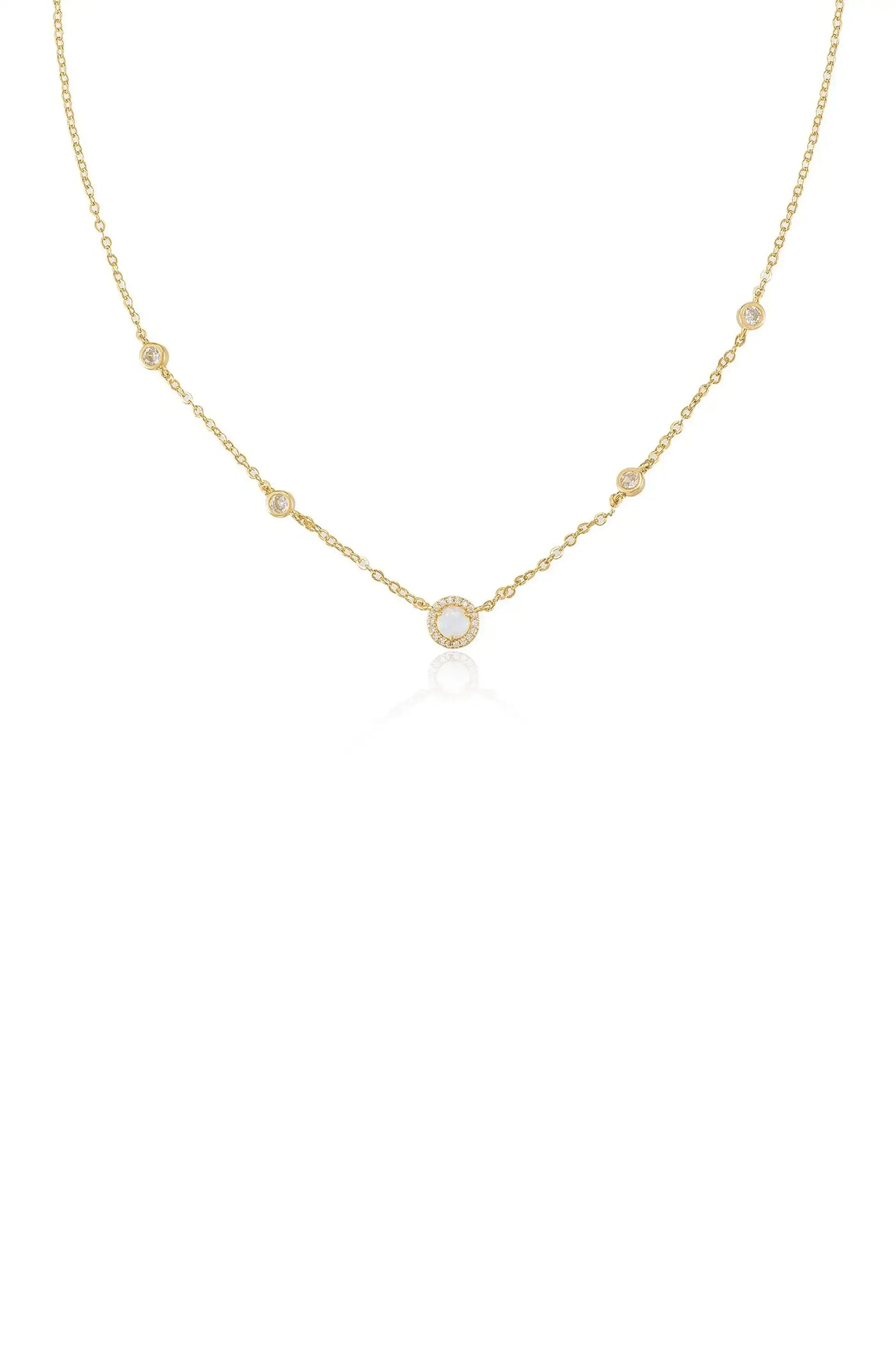 A delicate gold necklace features a circular pendant surrounded by smaller stones, elegantly draping with a reflective sheen against a plain white background.