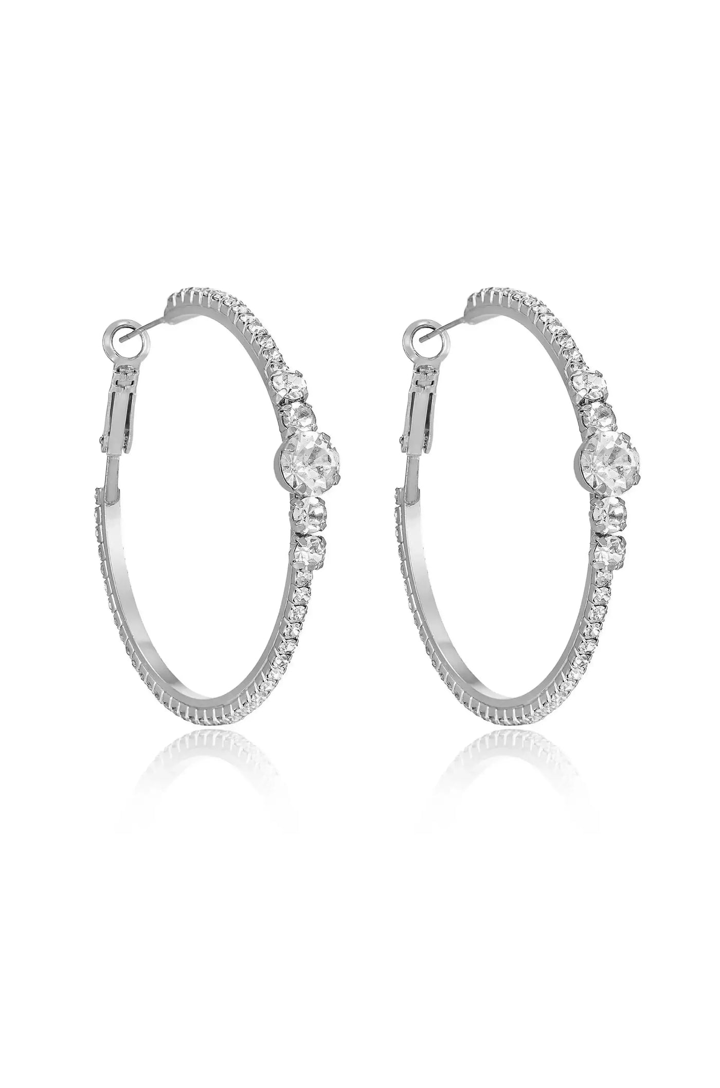Silver hoop earrings decorated with sparkling gemstones are displayed prominently. The reflective surface enhances their shine, creating an elegant appearance suitable for special occasions or everyday wear.