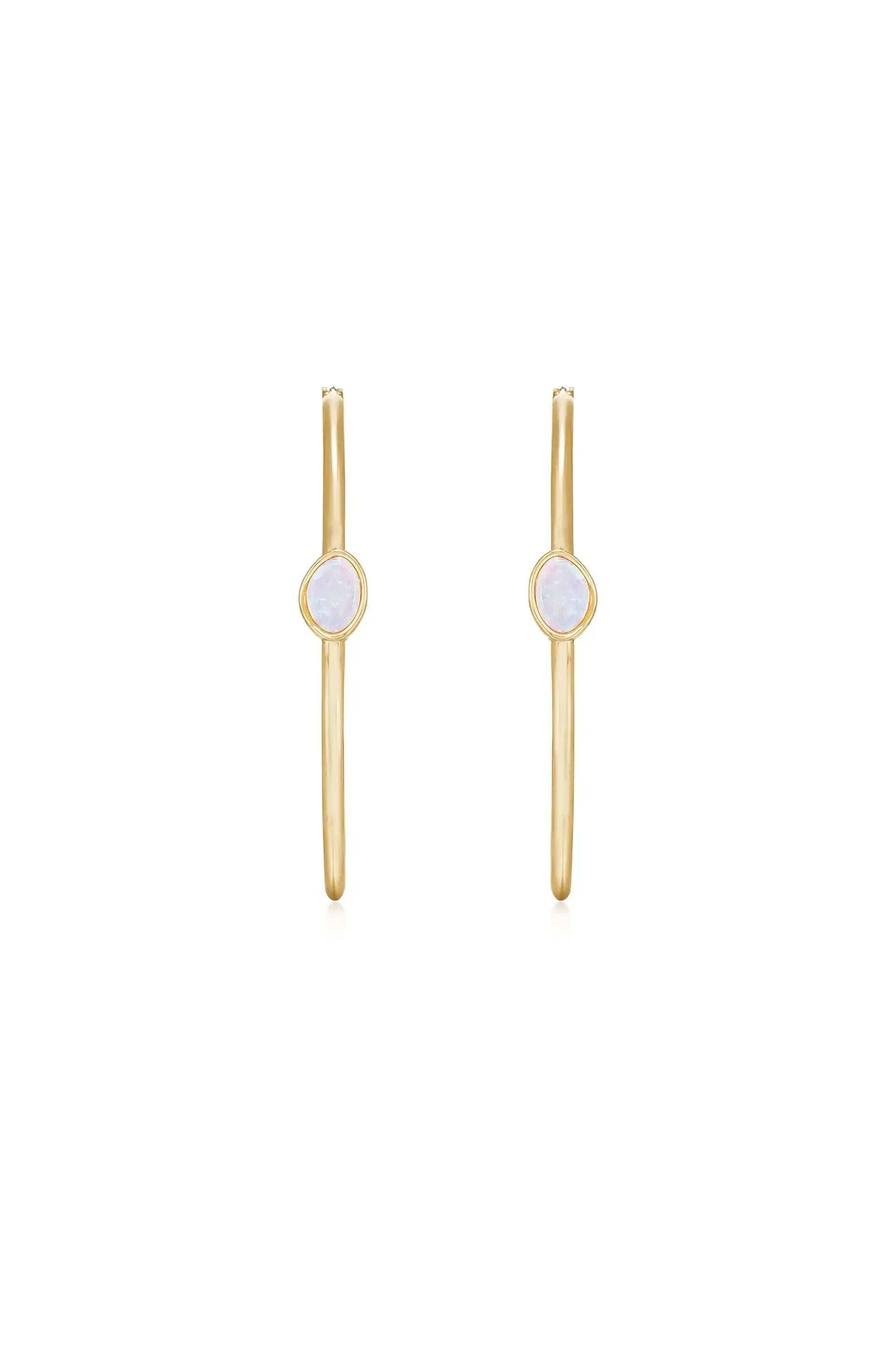 Gold hoop earrings feature an oval shaped gemstone in the center. They are displayed against a plain white background, emphasizing their simple and elegant design.