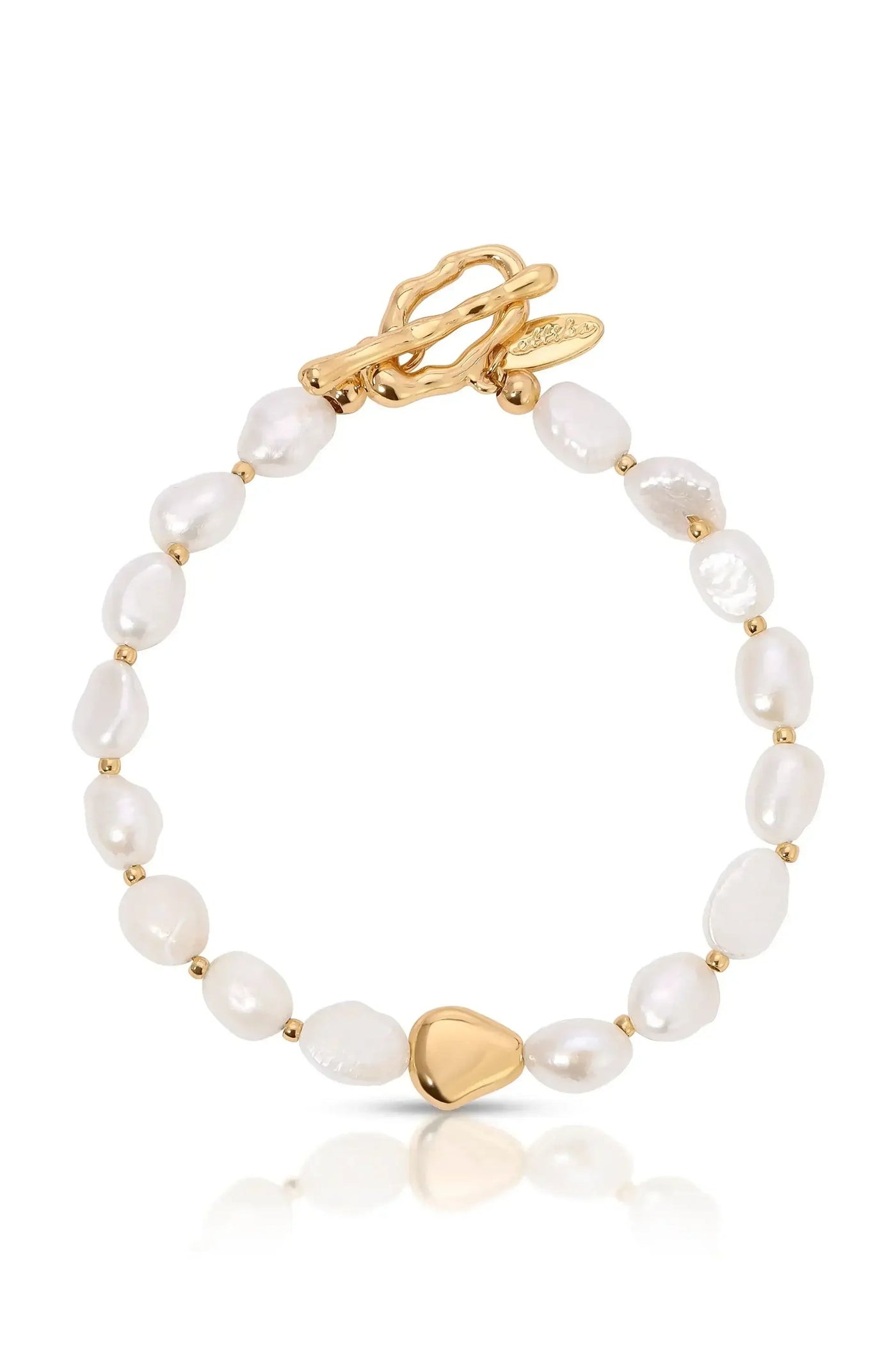 A pearl bracelet features irregularly shaped white pearls interspersed with small gold beads, culminating in a triangular gold clasp. The piece rests on a reflective surface, showcasing its elegance.