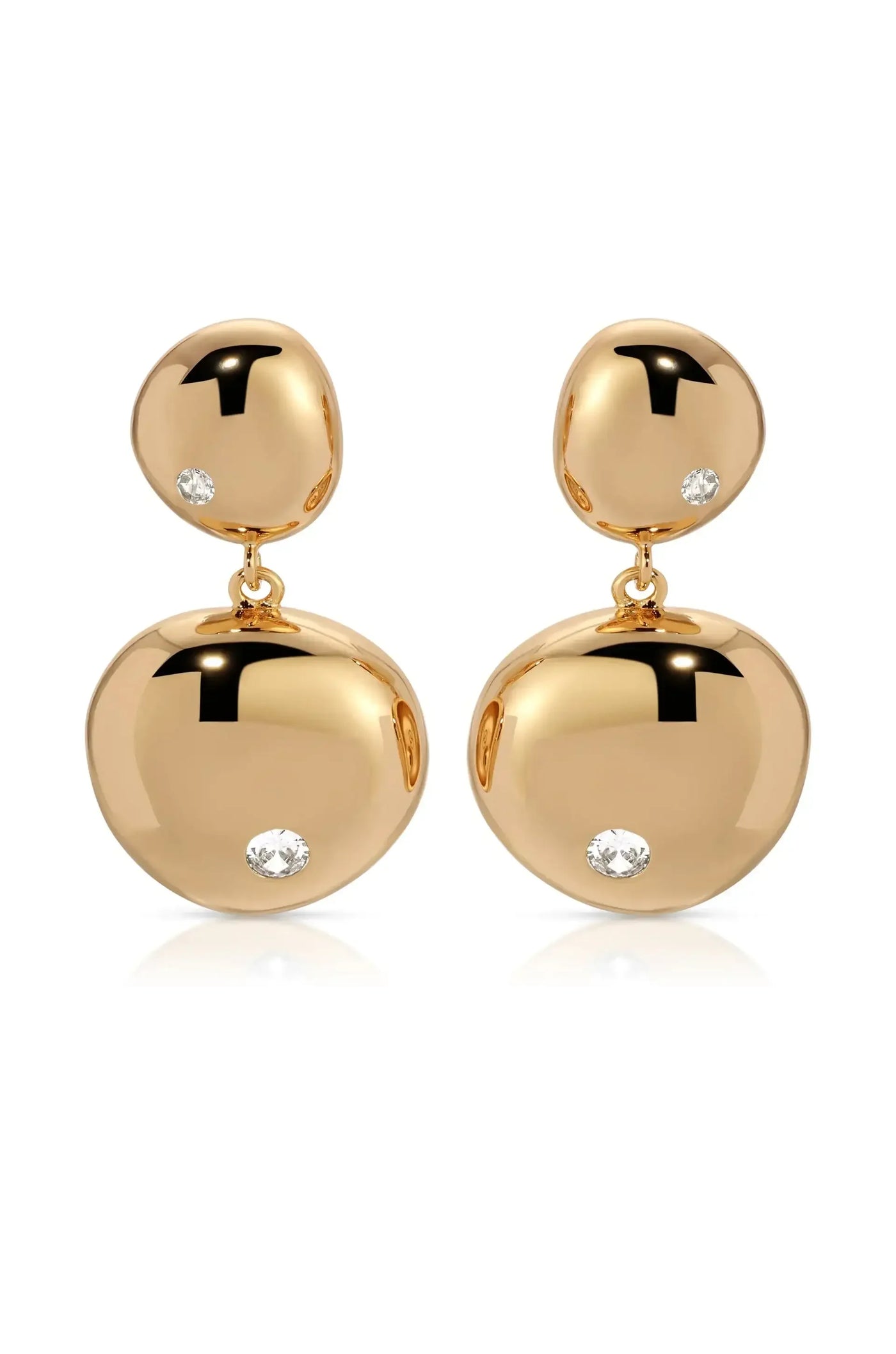 Two gold earrings dangle elegantly, featuring polished, rounded shapes adorned with small, sparkling diamonds. They rest on a white surface, reflecting light and enhancing their luxurious appearance.