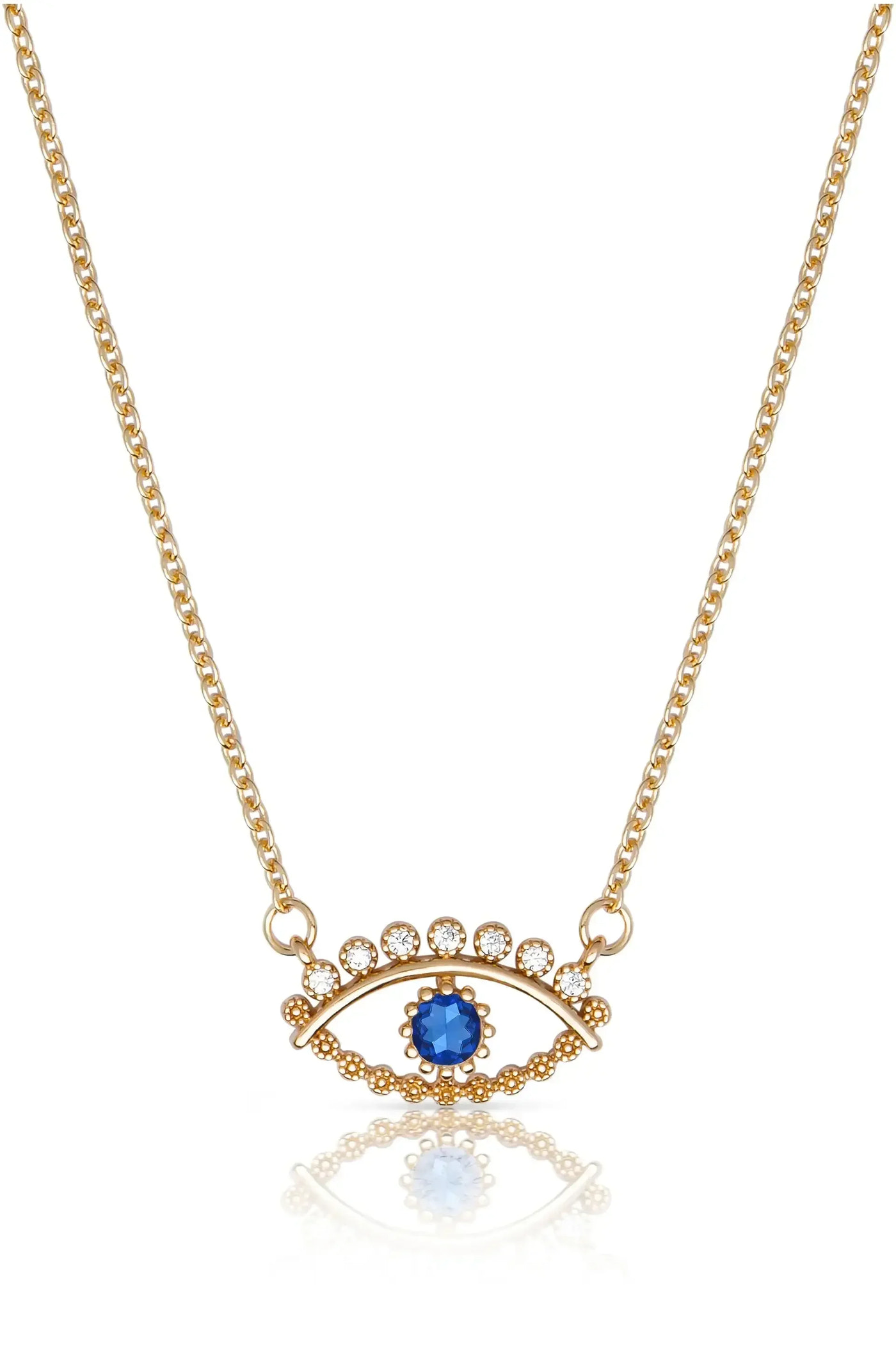 A golden necklace features a blue gemstone and sparkling circular decorations arranged in an eye shape, resting on a reflective surface, showcasing its intricate design and elegance.
