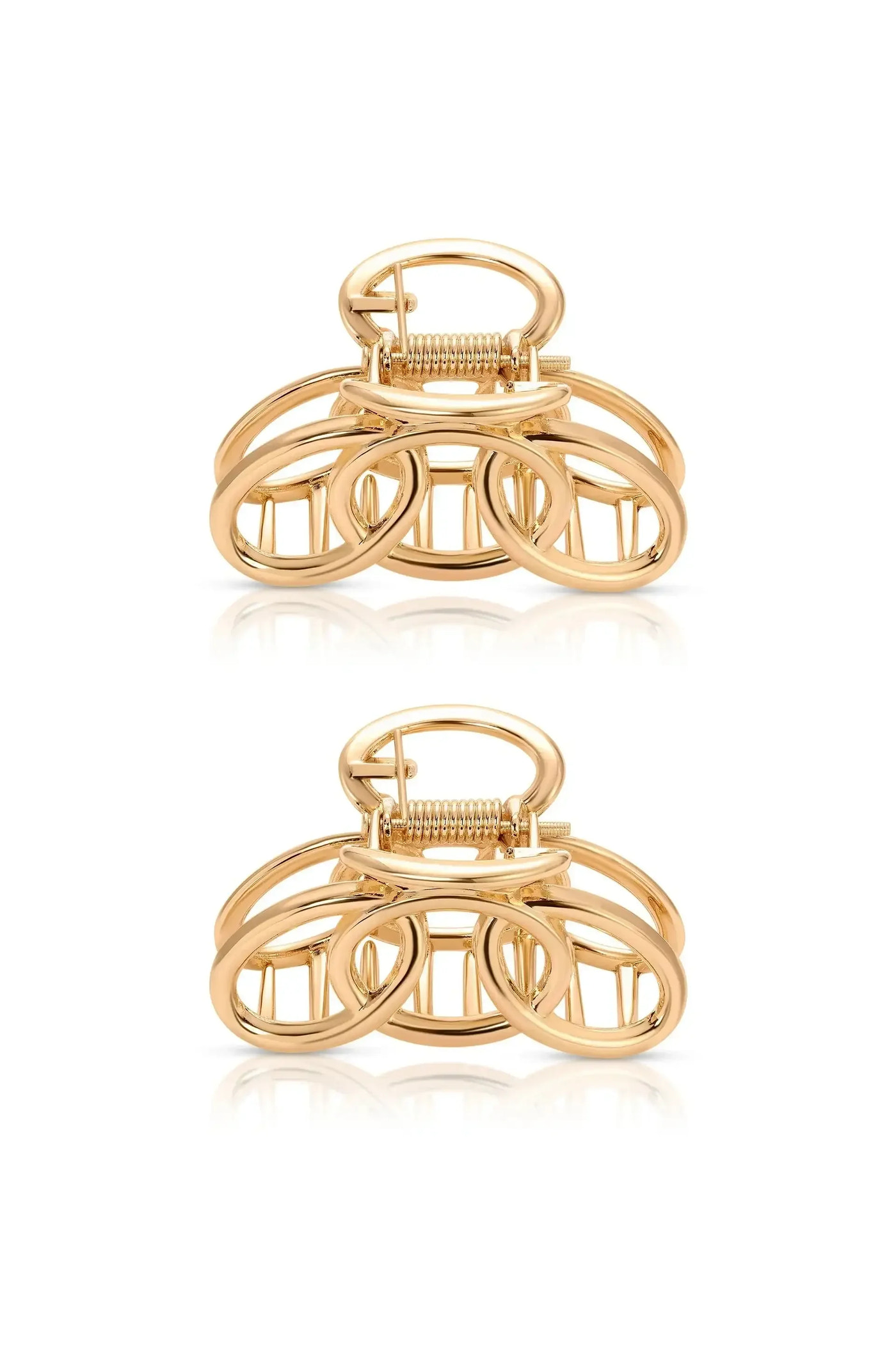 A golden hair clip featuring intertwined circular shapes sits centered, showcasing its reflective surface against a plain white background, emphasizing its design and texture.