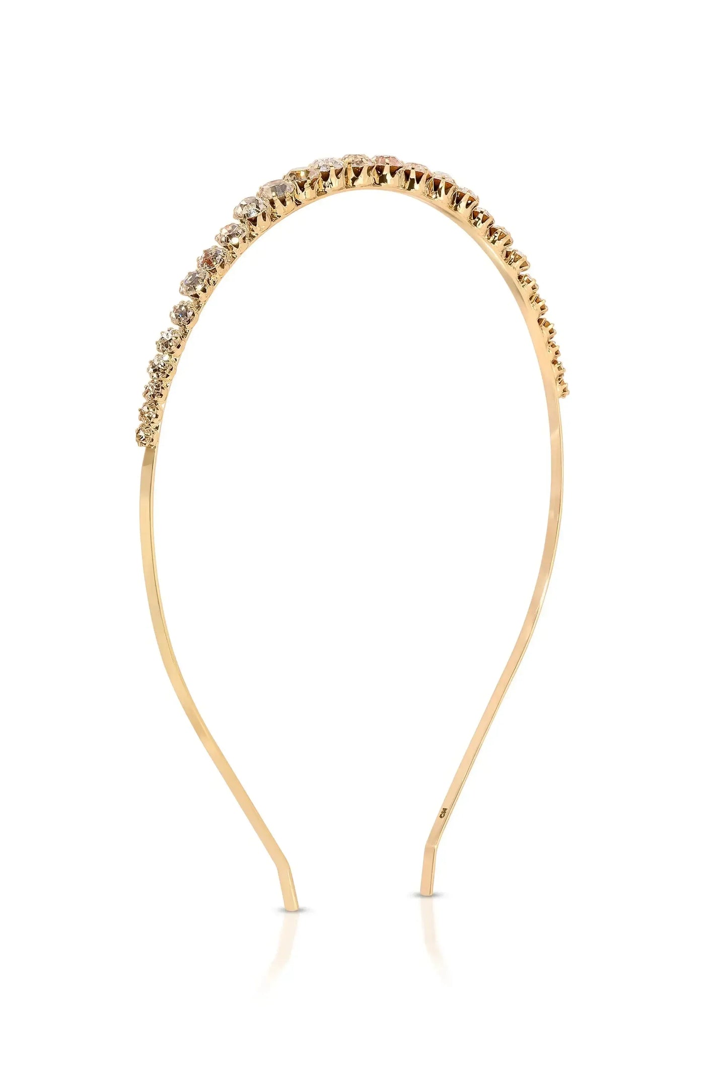 A gold headband adorned with sparkling stones rests upright against a reflective surface, showcasing its elegant design and shine in a minimalist setting.