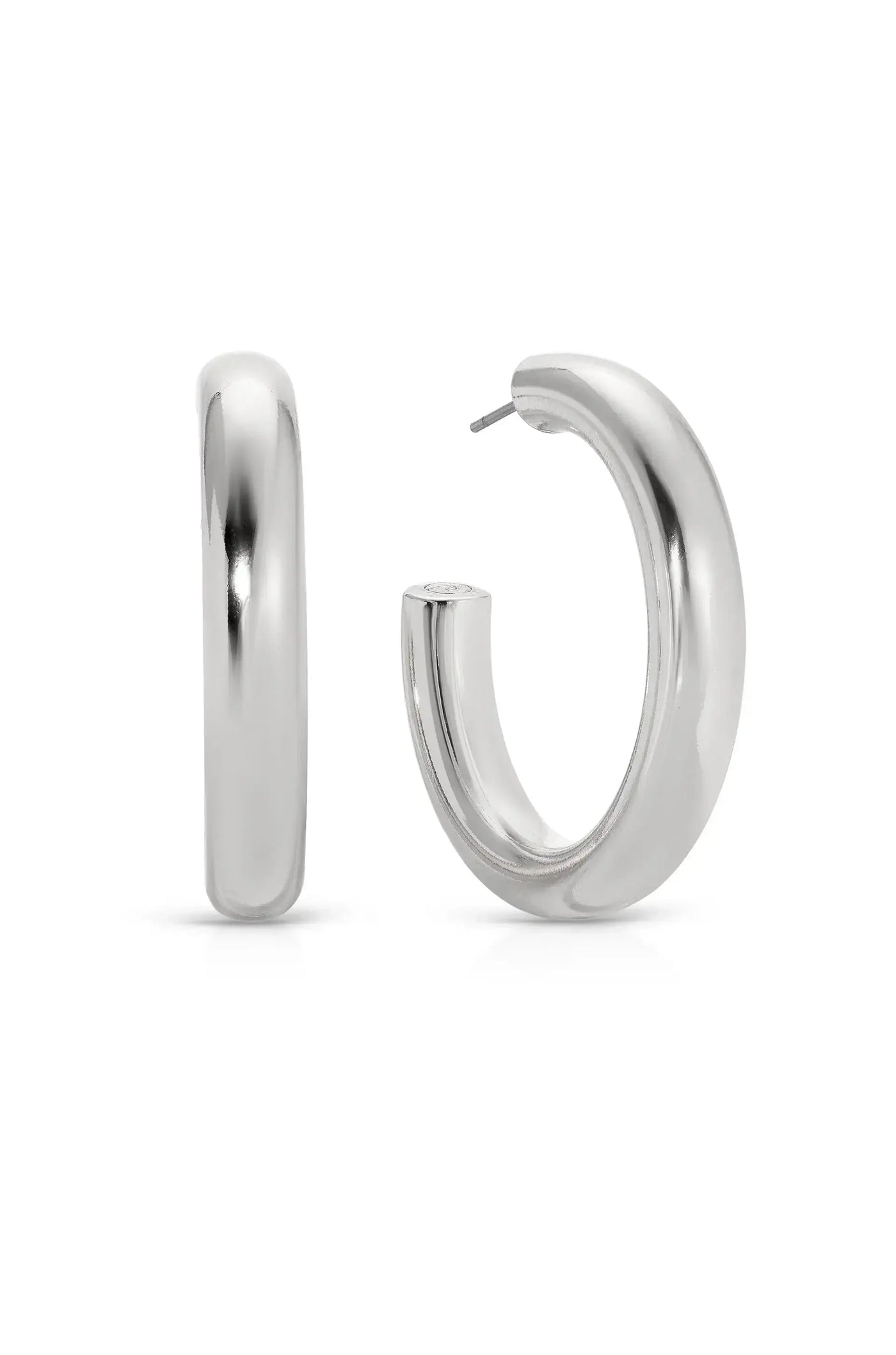 A pair of shiny silver hoop earrings stands upright against a white background. One earring is positioned sideways, while the other is partially turned to show its opening for fastening.