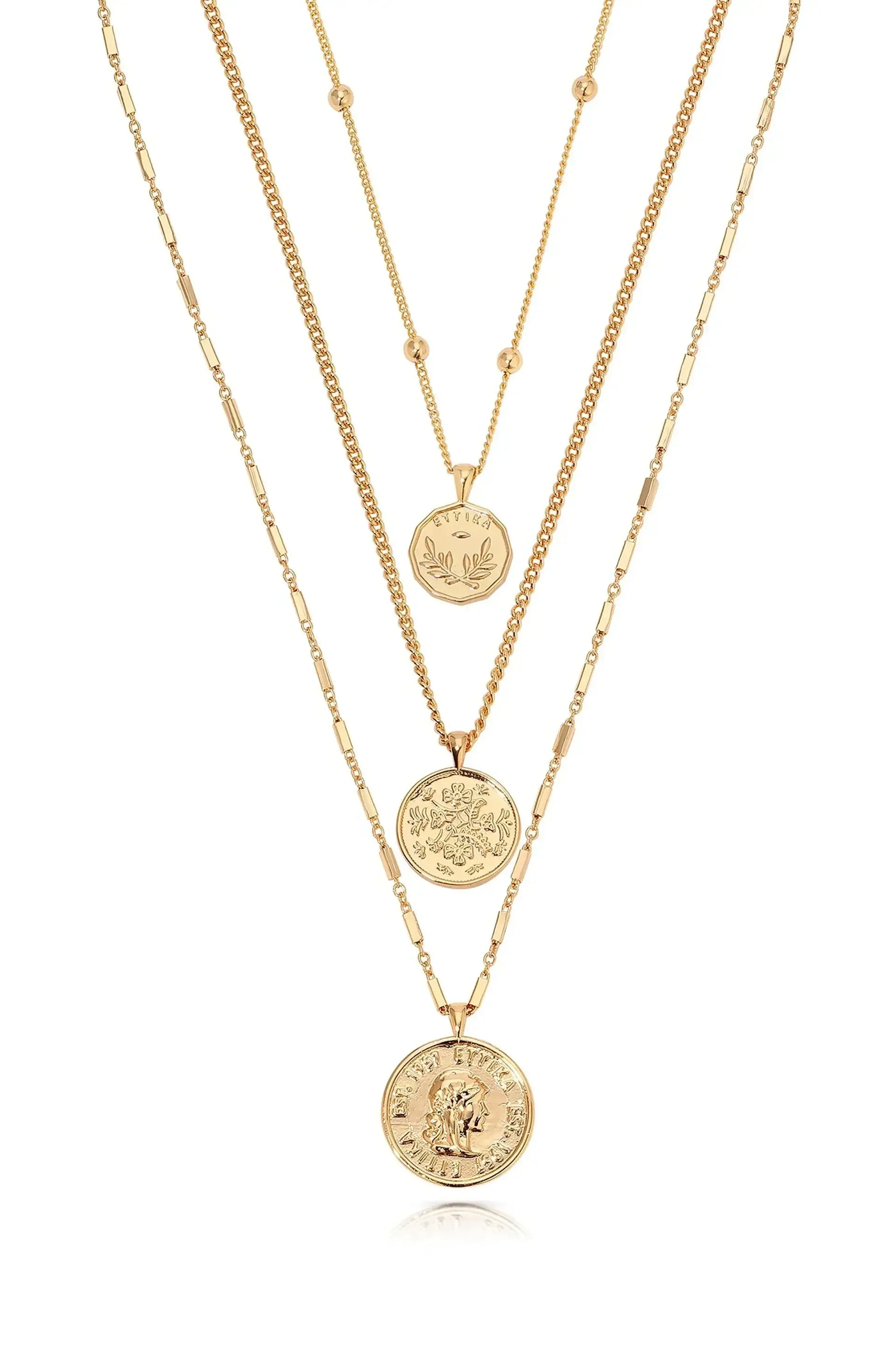Three layered gold necklaces are displayed. Each necklace features circular pendants with intricate designs, hanging gracefully against a neutral background, showcasing their elegance and shine.